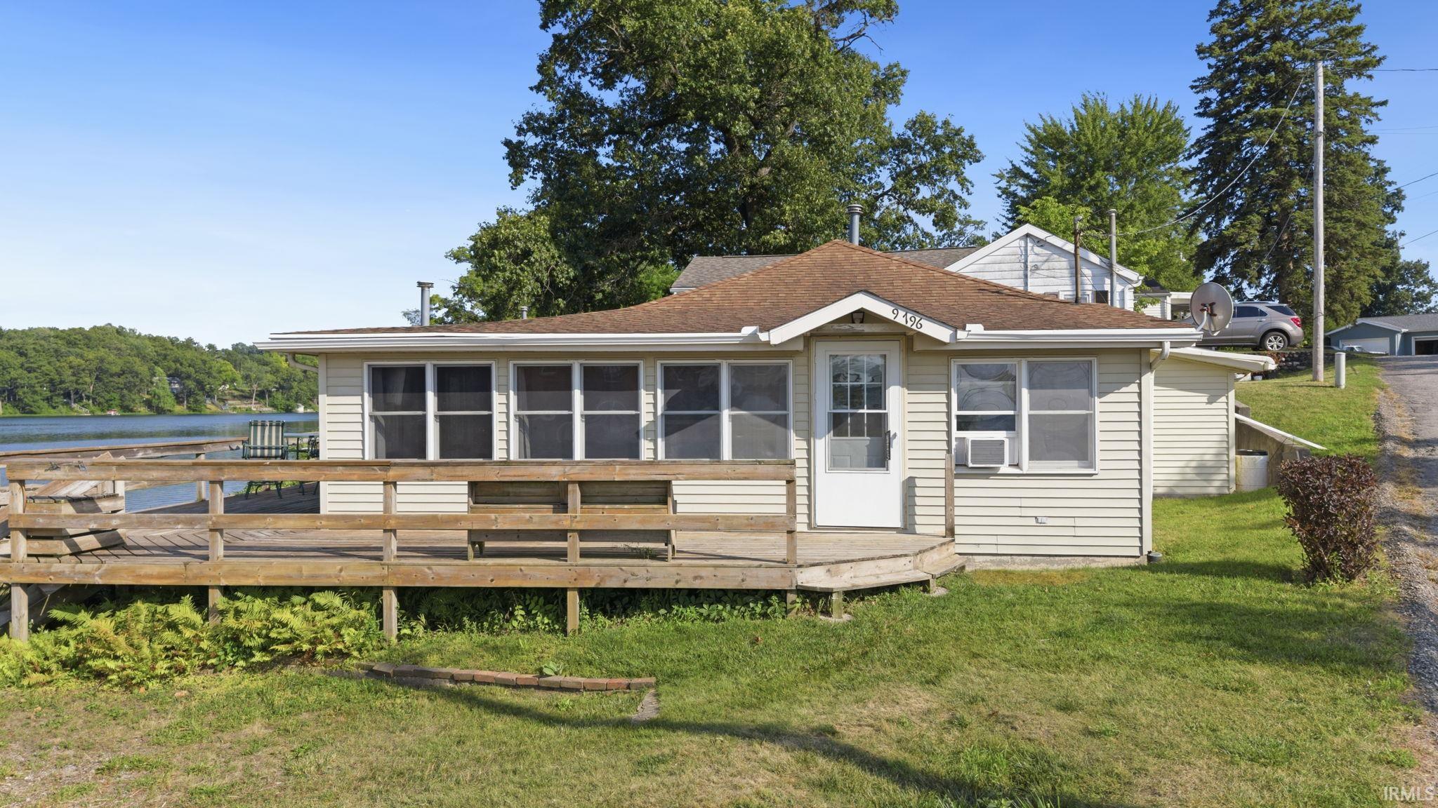 Waterfront property featuring a spacious wood deck, direct water access, and a pier