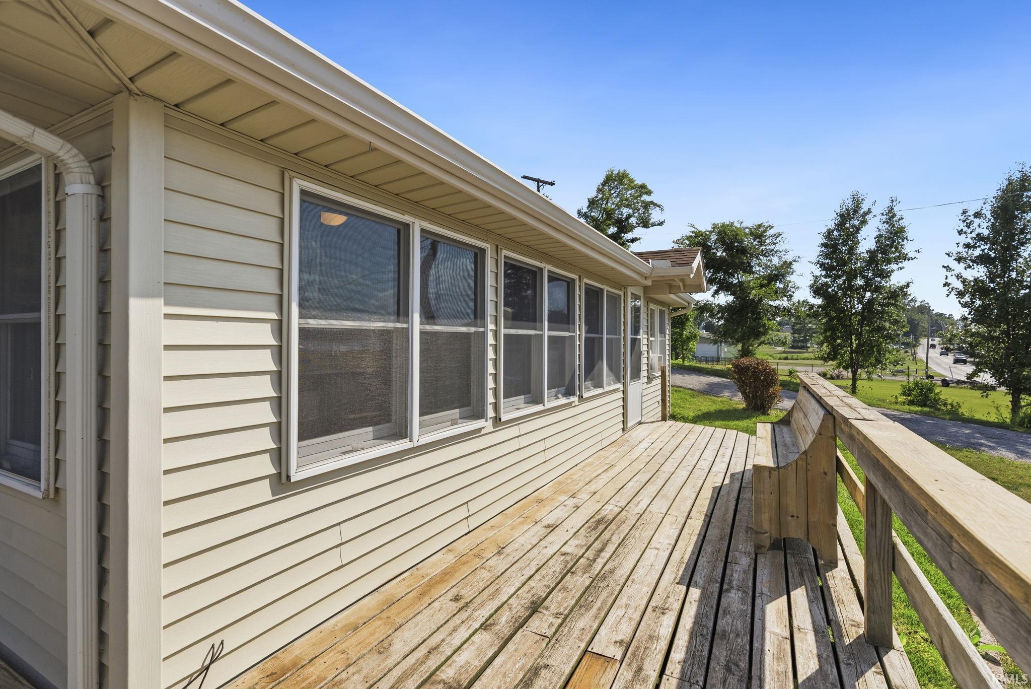 Exterior wood deck with built-in wooden bench seating, featuring a wooden railing