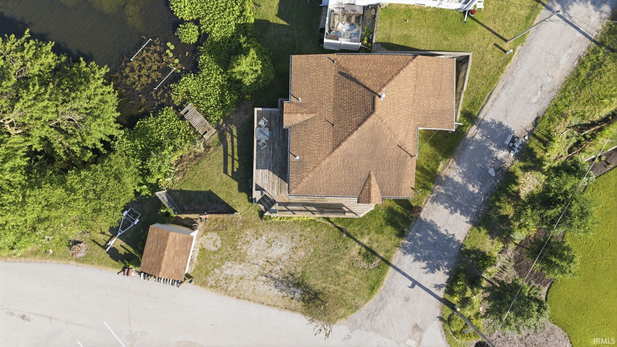 Gabled roof residence featuring a waterside location with a dock, mature trees, and an accessory structure