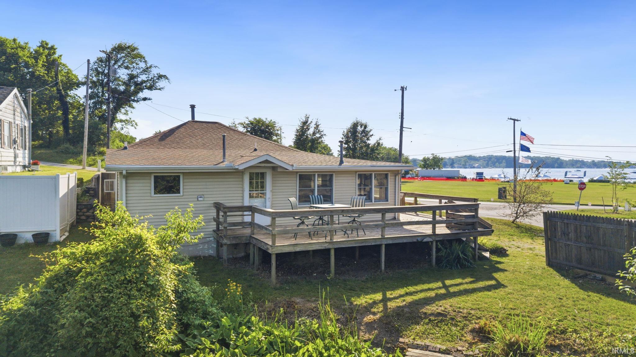 Rear exterior featuring a spacious wood deck, beige siding, and a brown shingle roof