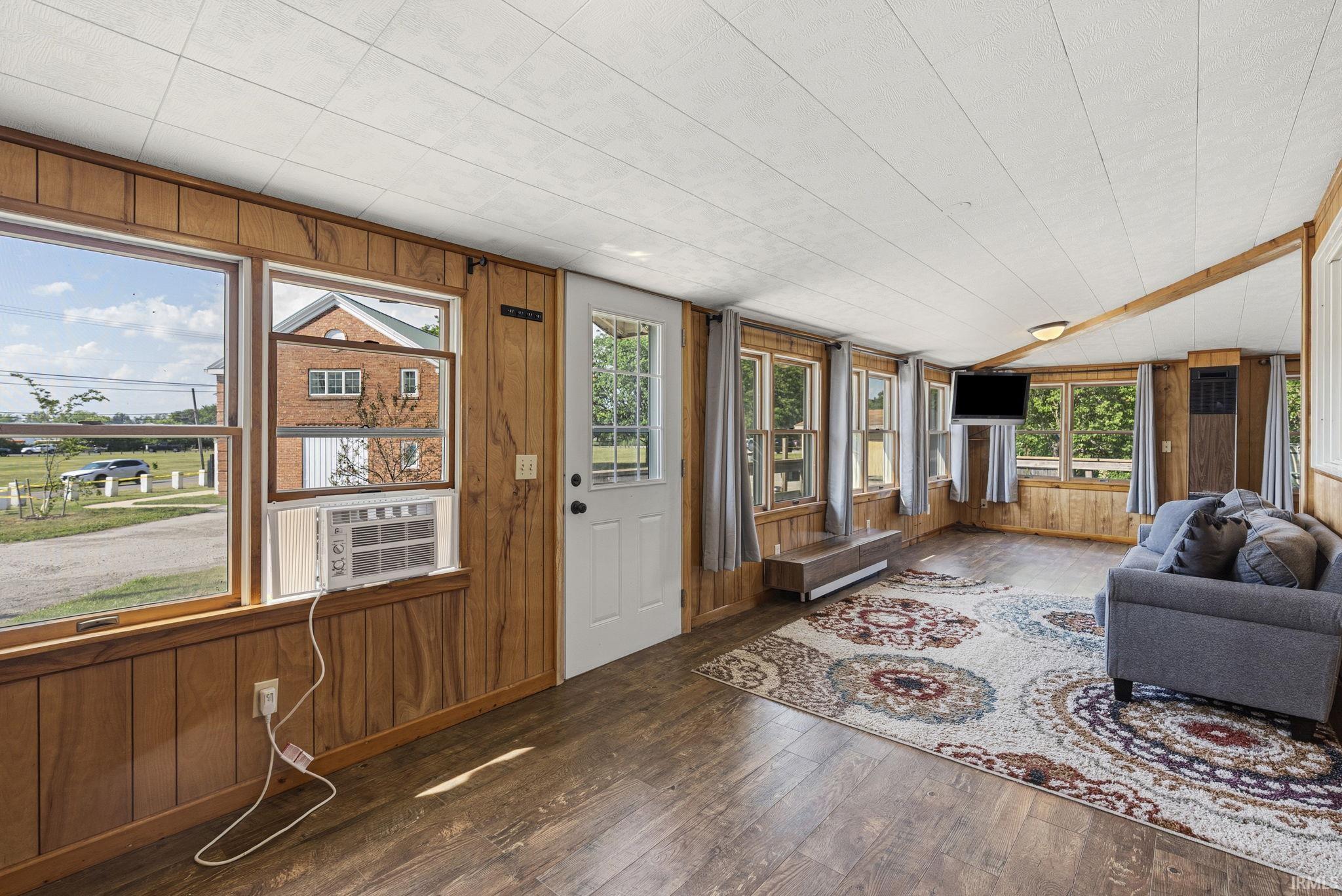 Spacious room featuring wood-finish paneling, multiple windows, and a white paneled ceiling