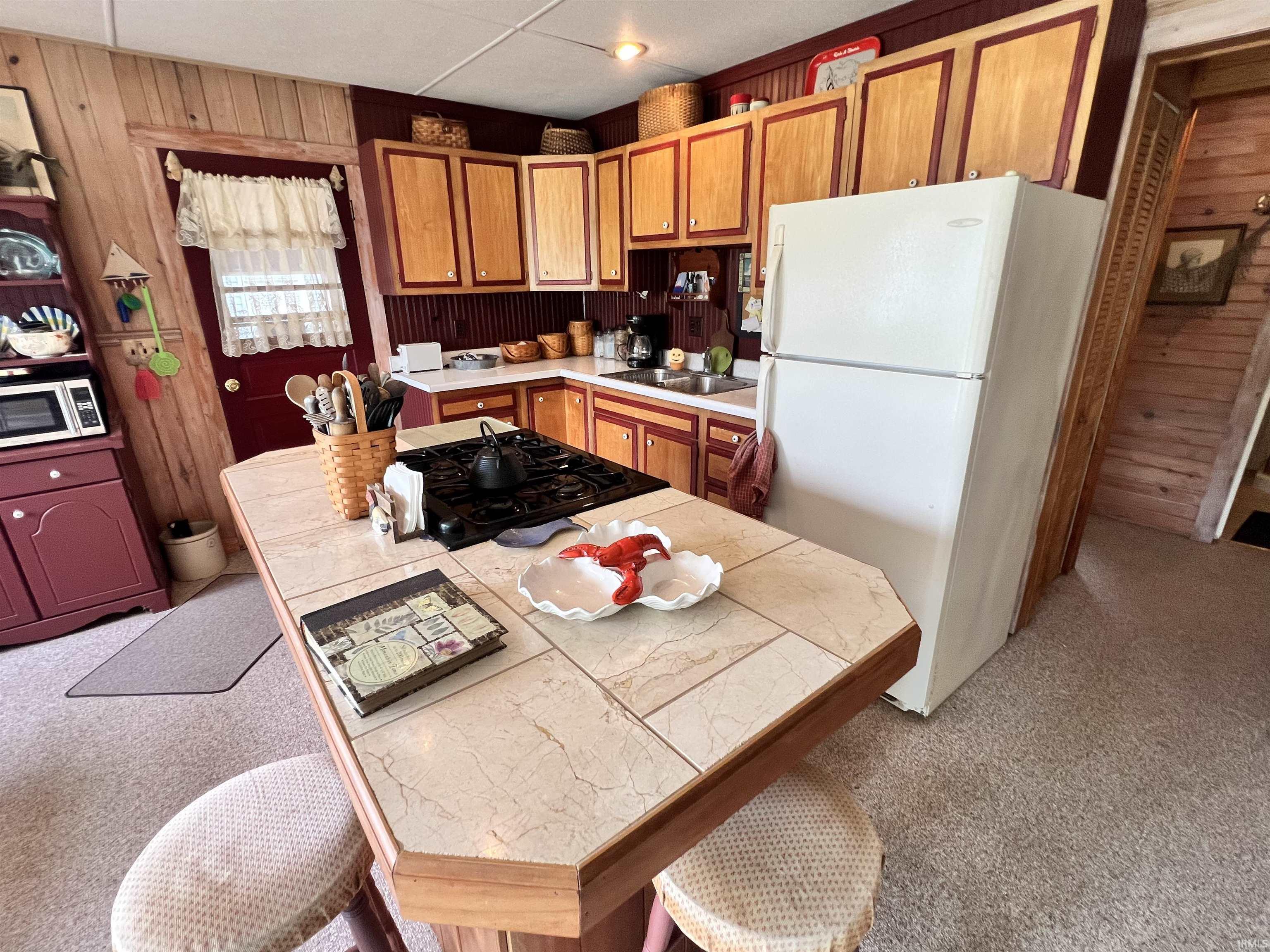 Kitchen featuring a central island with a tiled countertop, built-in gas range, and seating