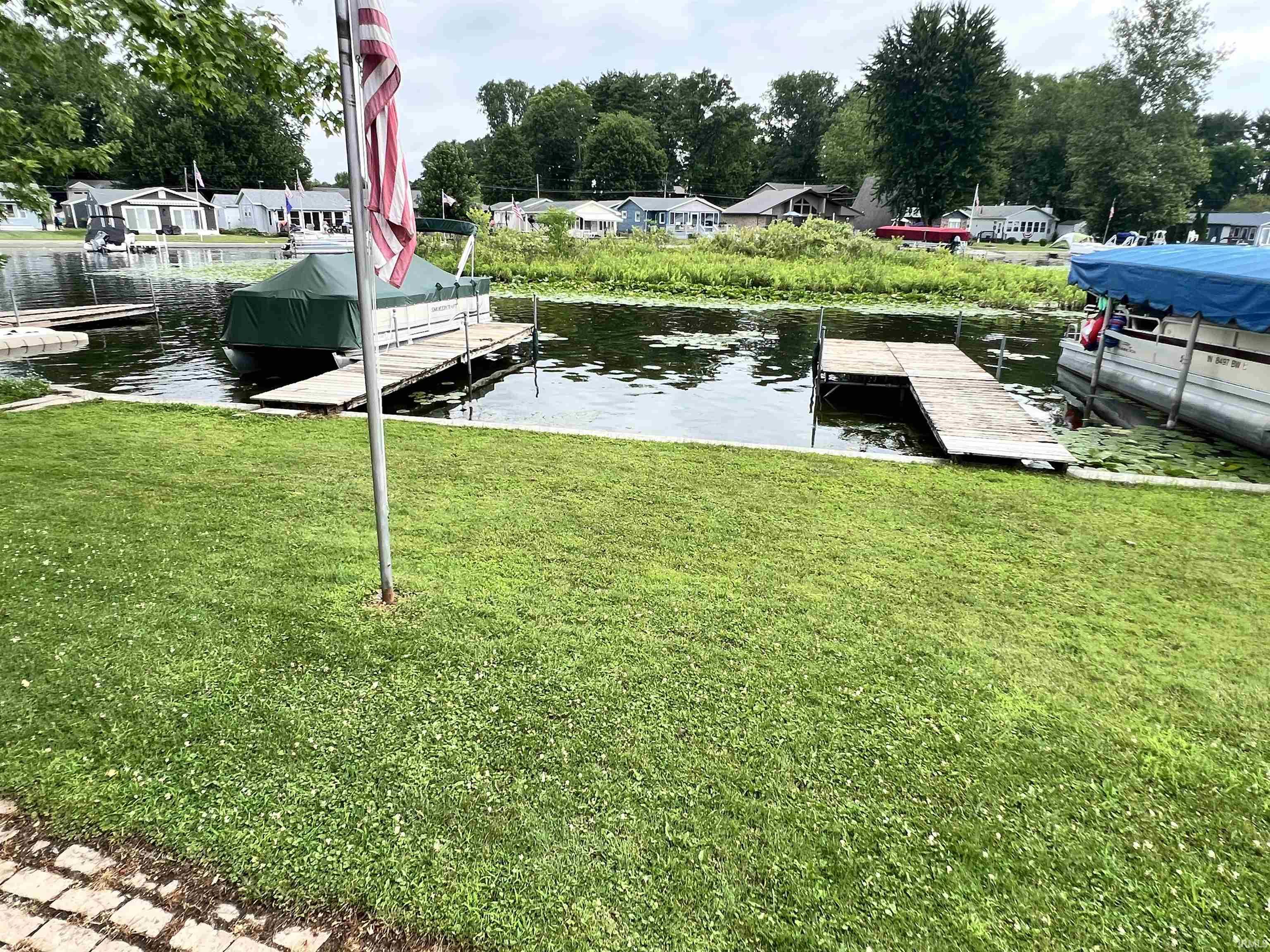 Waterfront property featuring two private docks, a verdant lawn, and a stone paver border