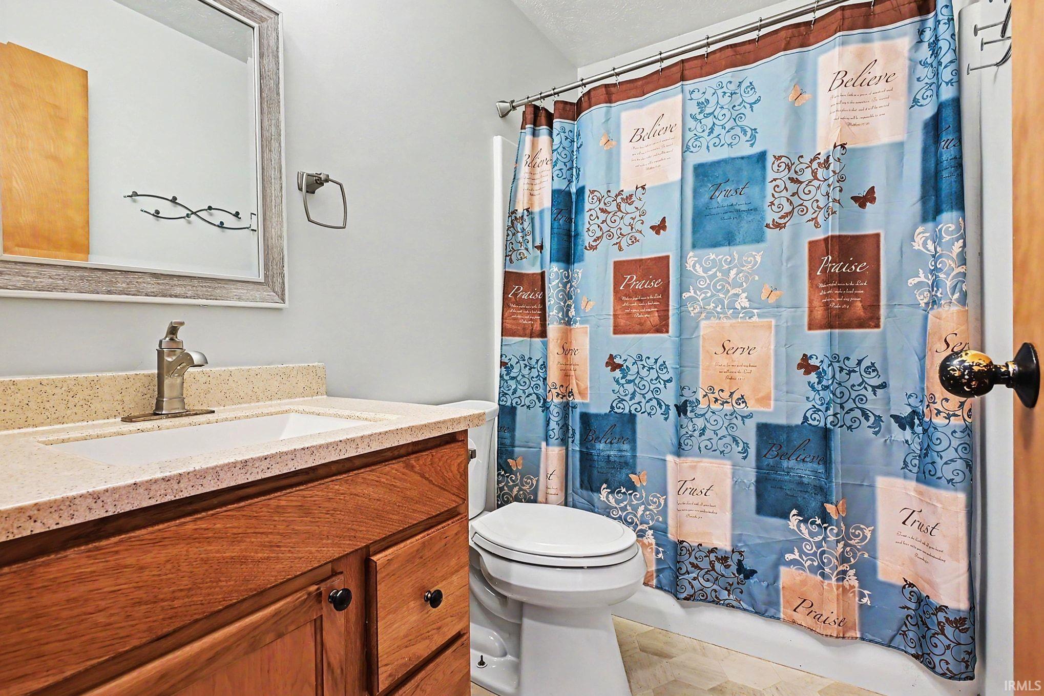 Bathroom featuring a wood-finish vanity with black hardware, a light-colored countertop, and an undermount sink