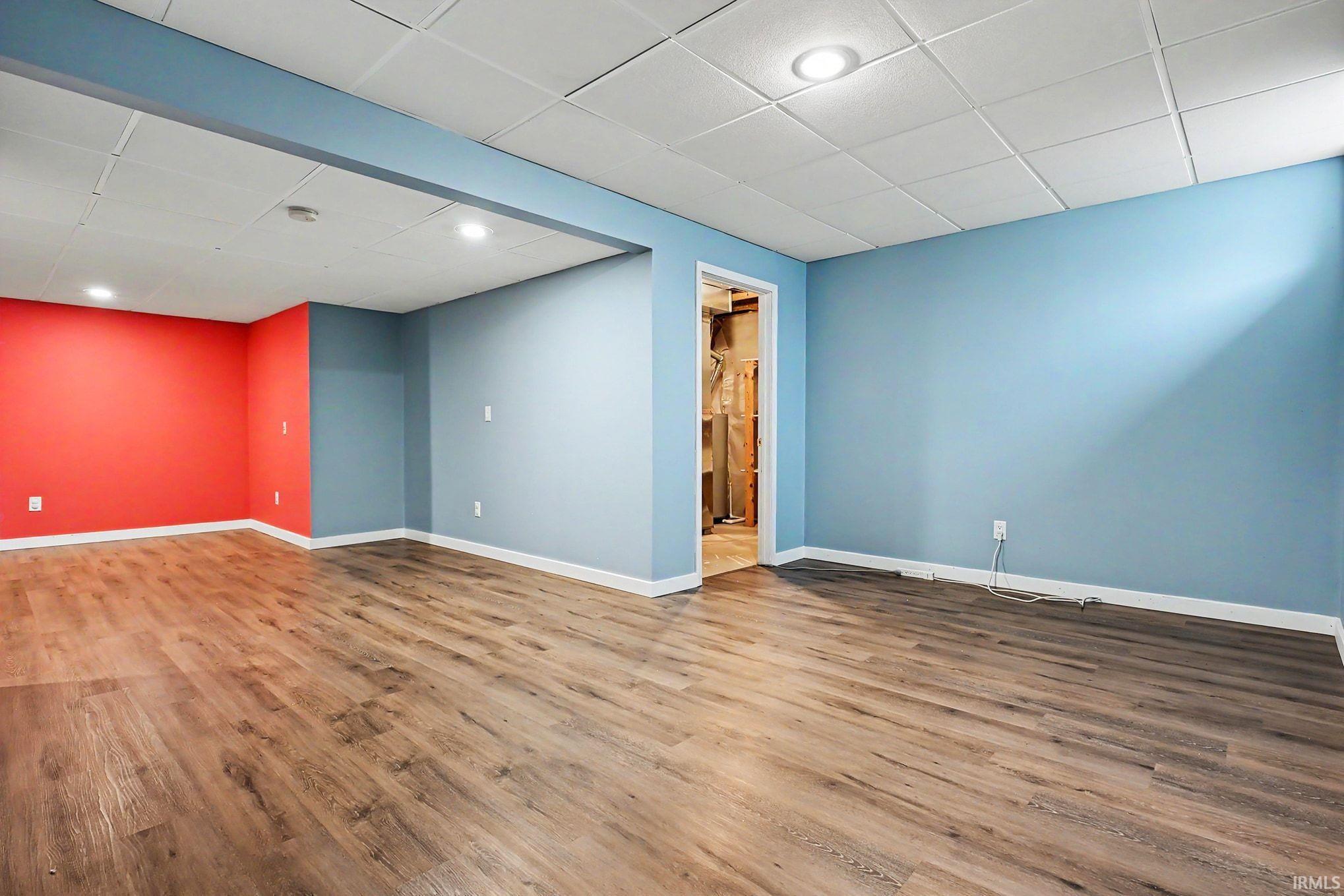 Finished basement space featuring wood-finish flooring, recessed lighting and drop ceiling.