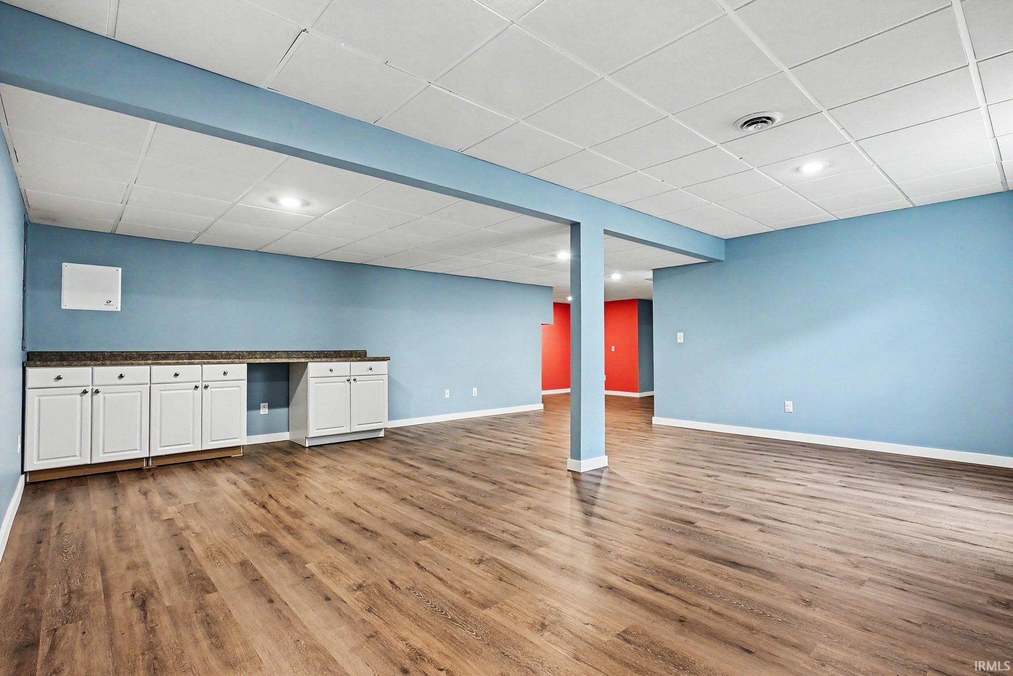 Spacious room featuring wood-finish flooring, recessed lighting, and a drop ceiling