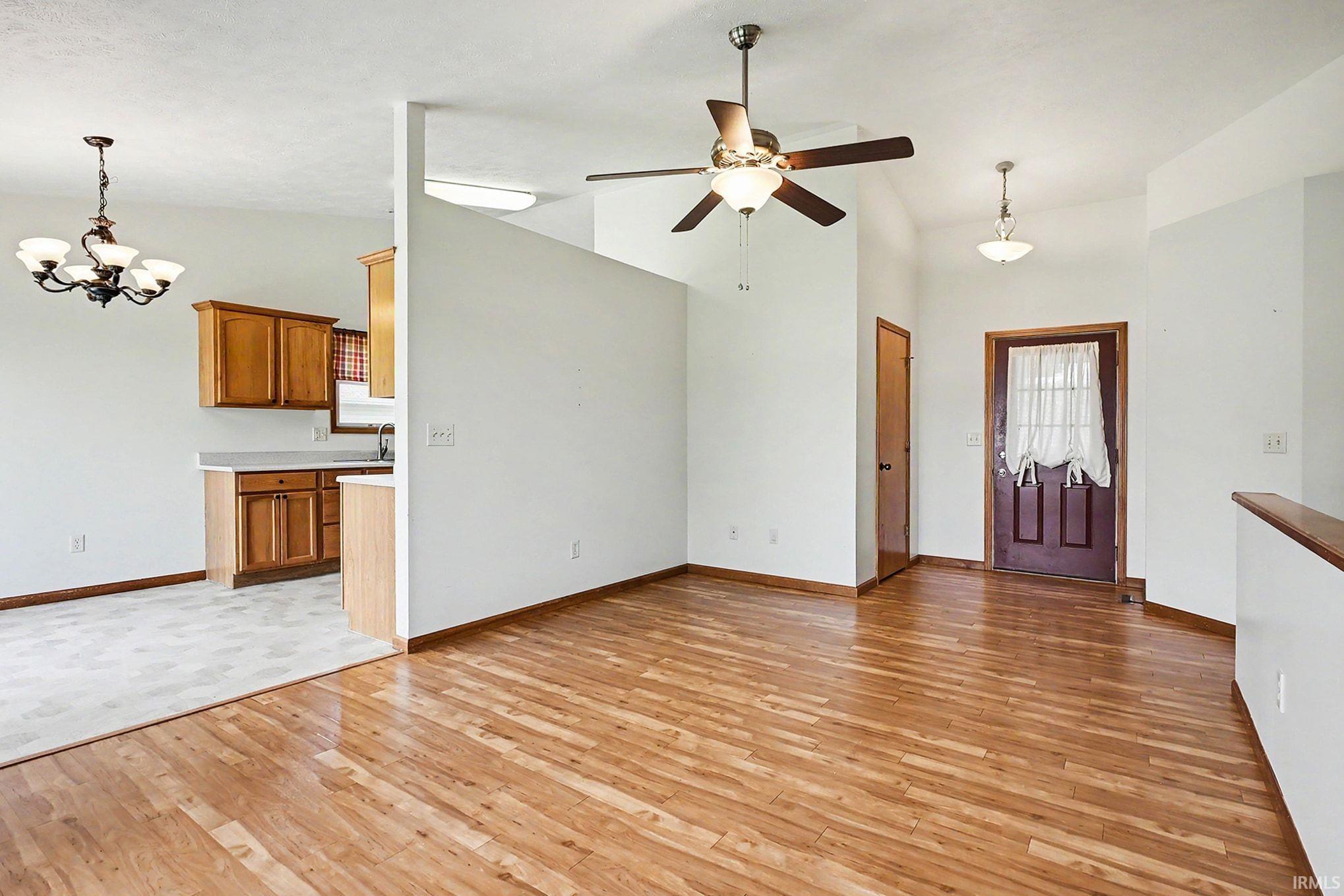 Open concept living space featuring wood-finish flooring with a ceiling fan and a front entry door with decorative glass