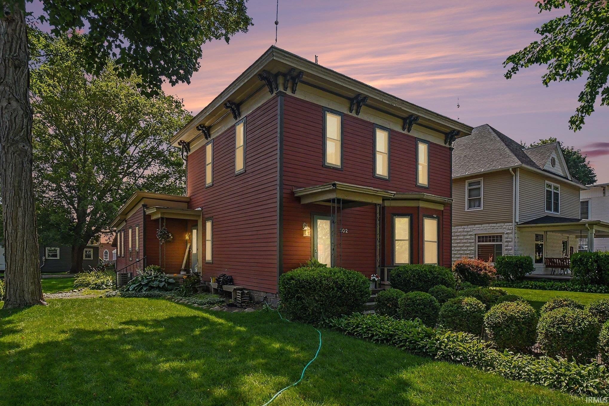 Classic two-story residence featuring a red siding exterior, contrasting cream trim, and decorative corbels