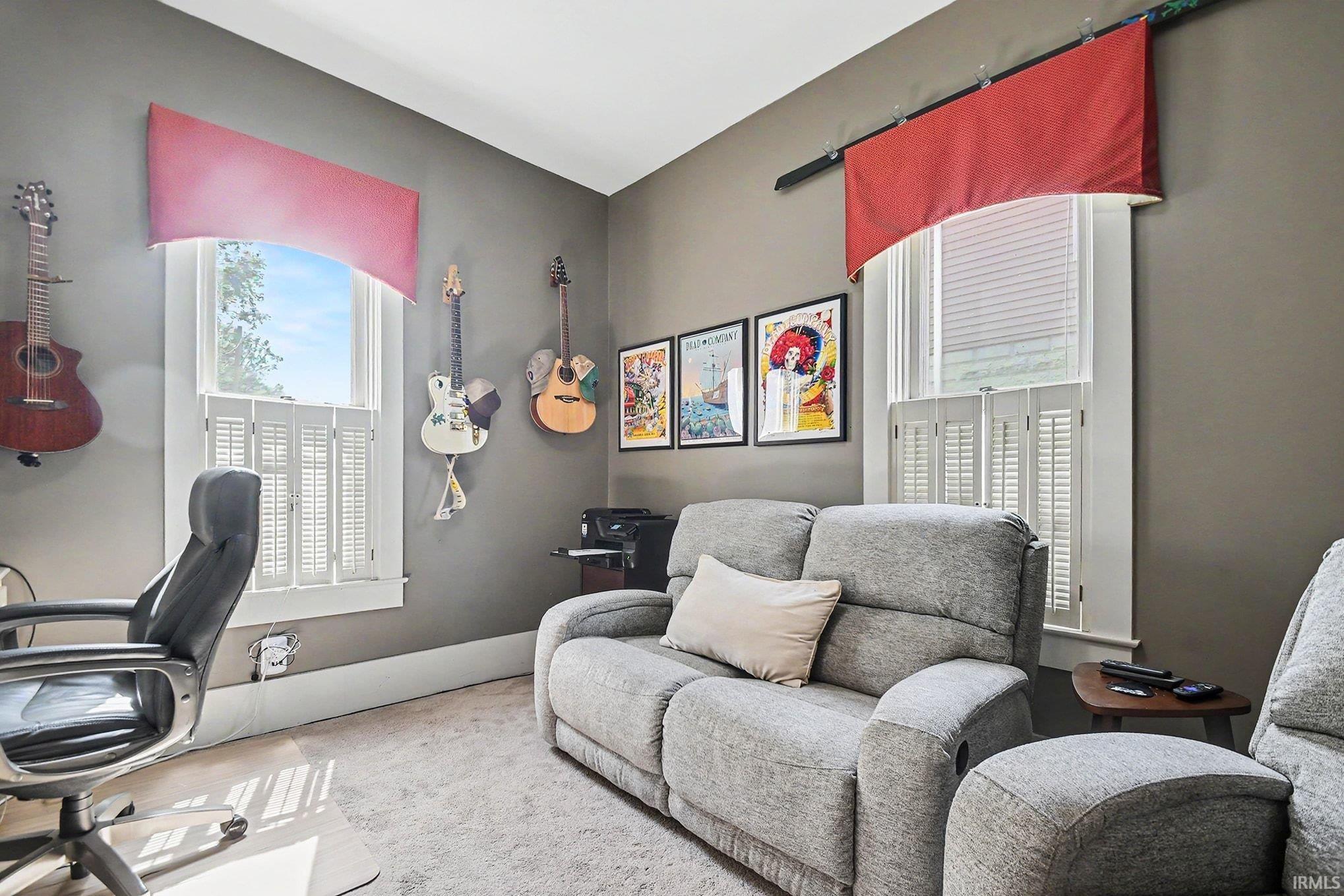 Bright room featuring two windows with white louvered shutters and coordinating valances