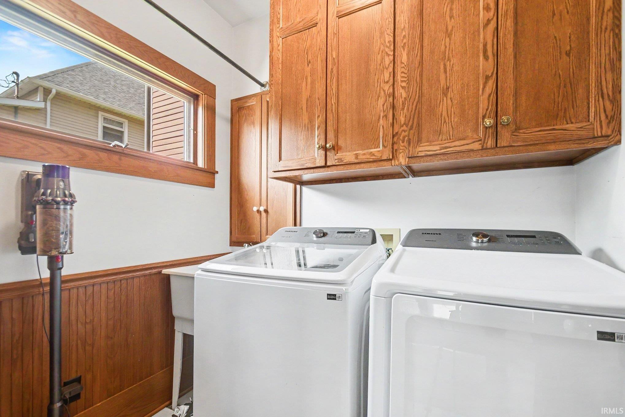 Utility room featuring wood-finish cabinetry, a white basin sink, and wood wainscoting