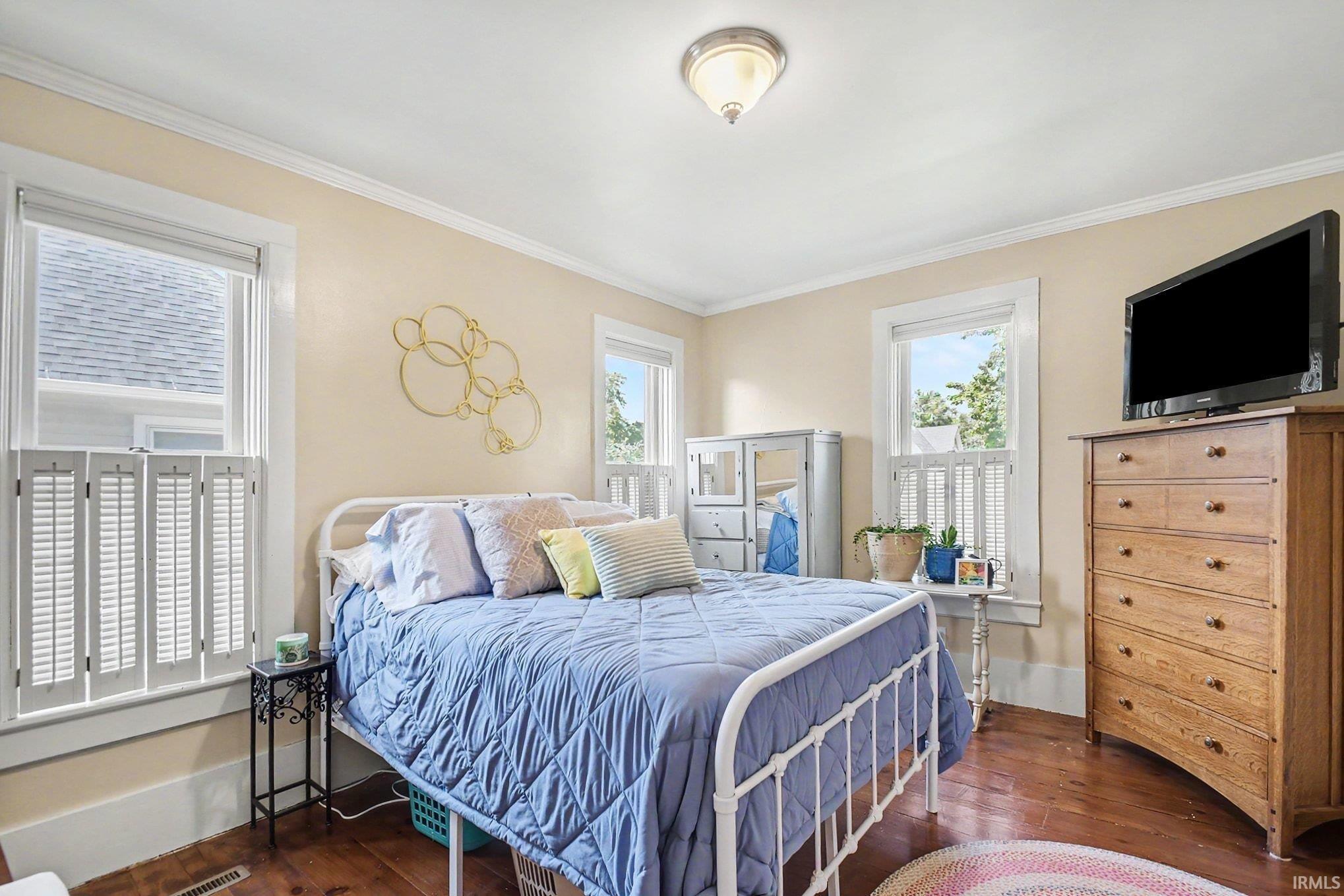 Bright room featuring rich wood flooring, multiple windows with white trim, and a ceiling-mounted light fixture