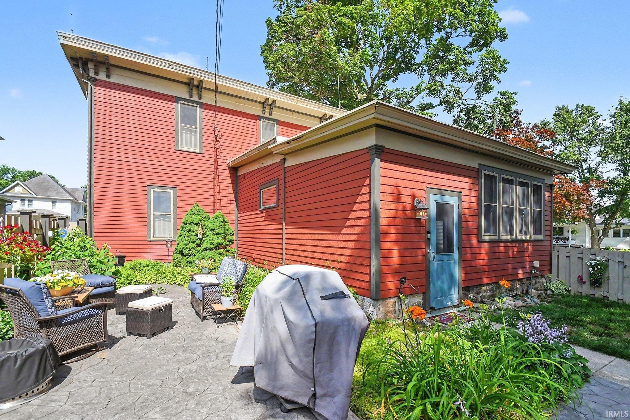 Exterior featuring red horizontal siding and an attached flat-roof extension