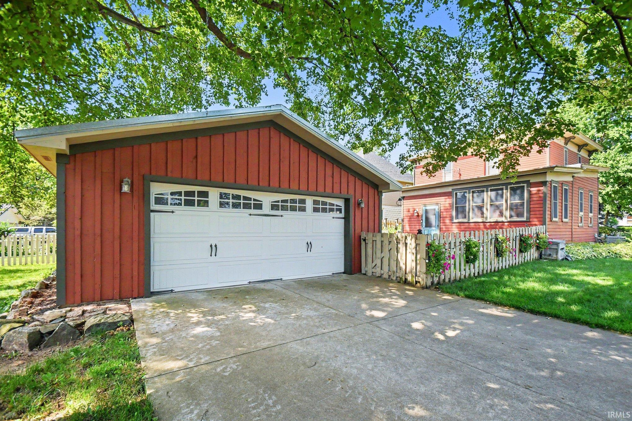 Detached red-sided garage with a white panel garage door and decorative handles