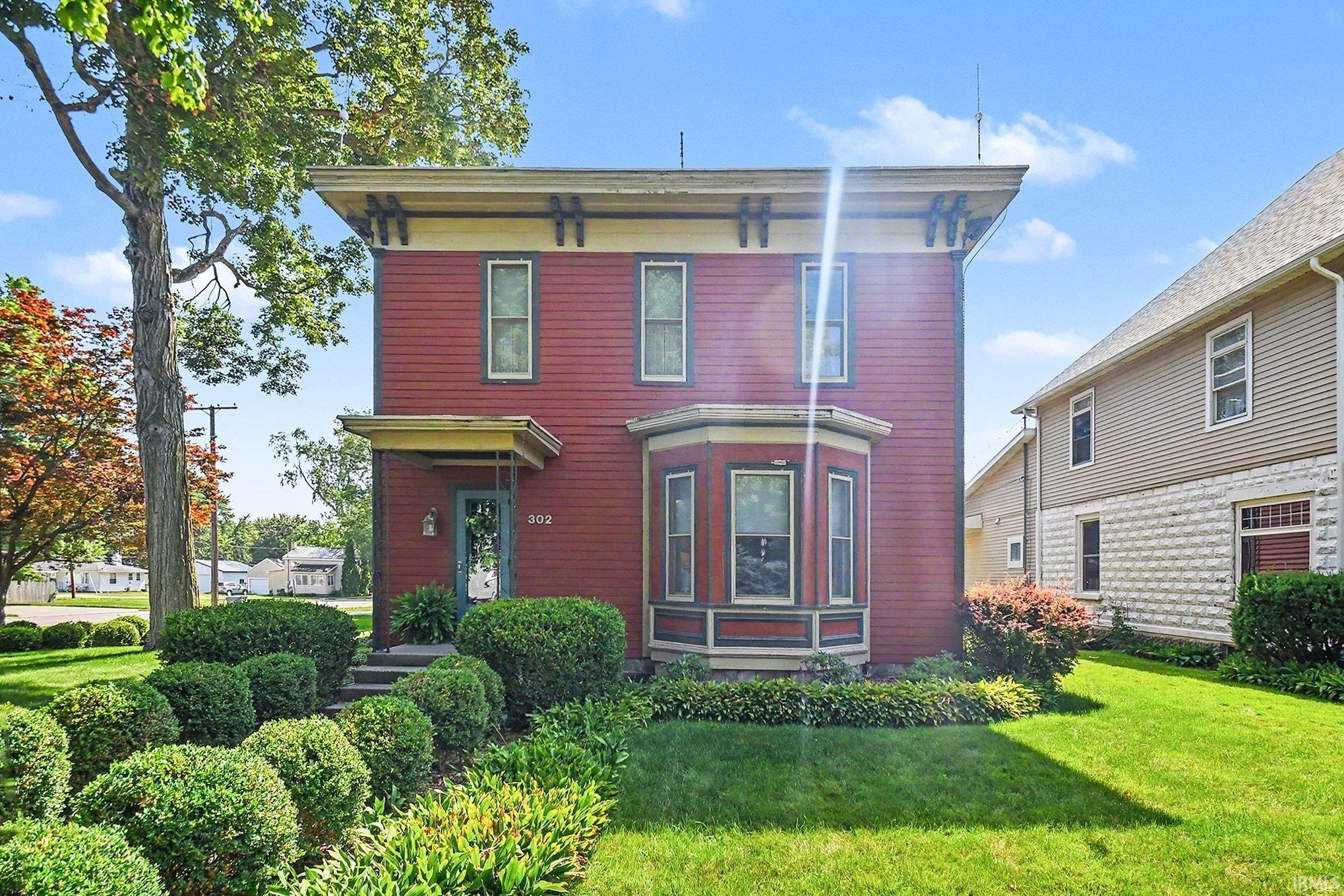 Two-story red clapboard residence featuring a prominent bay window