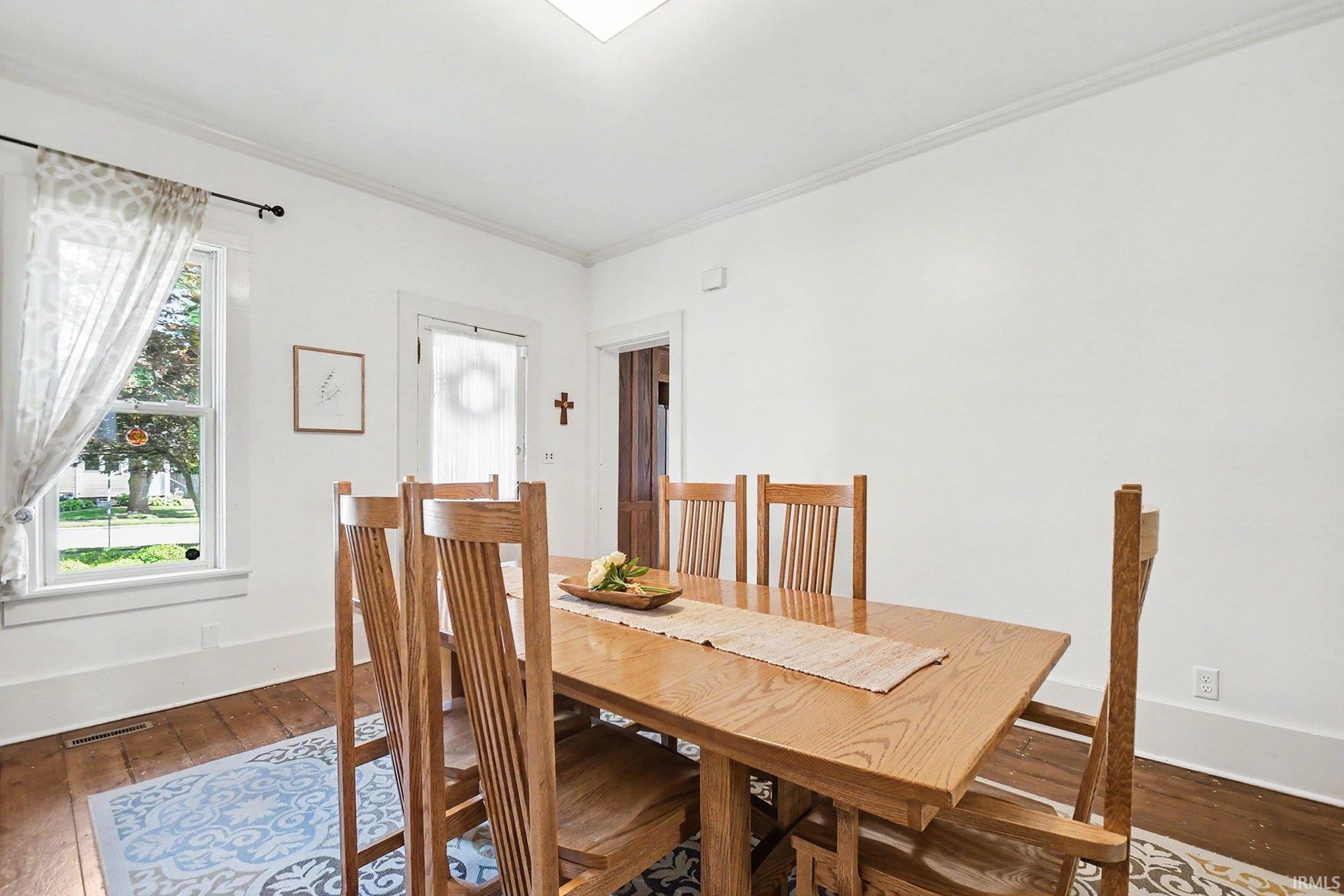 Hardwood flooring, crown molding, and white trim accents