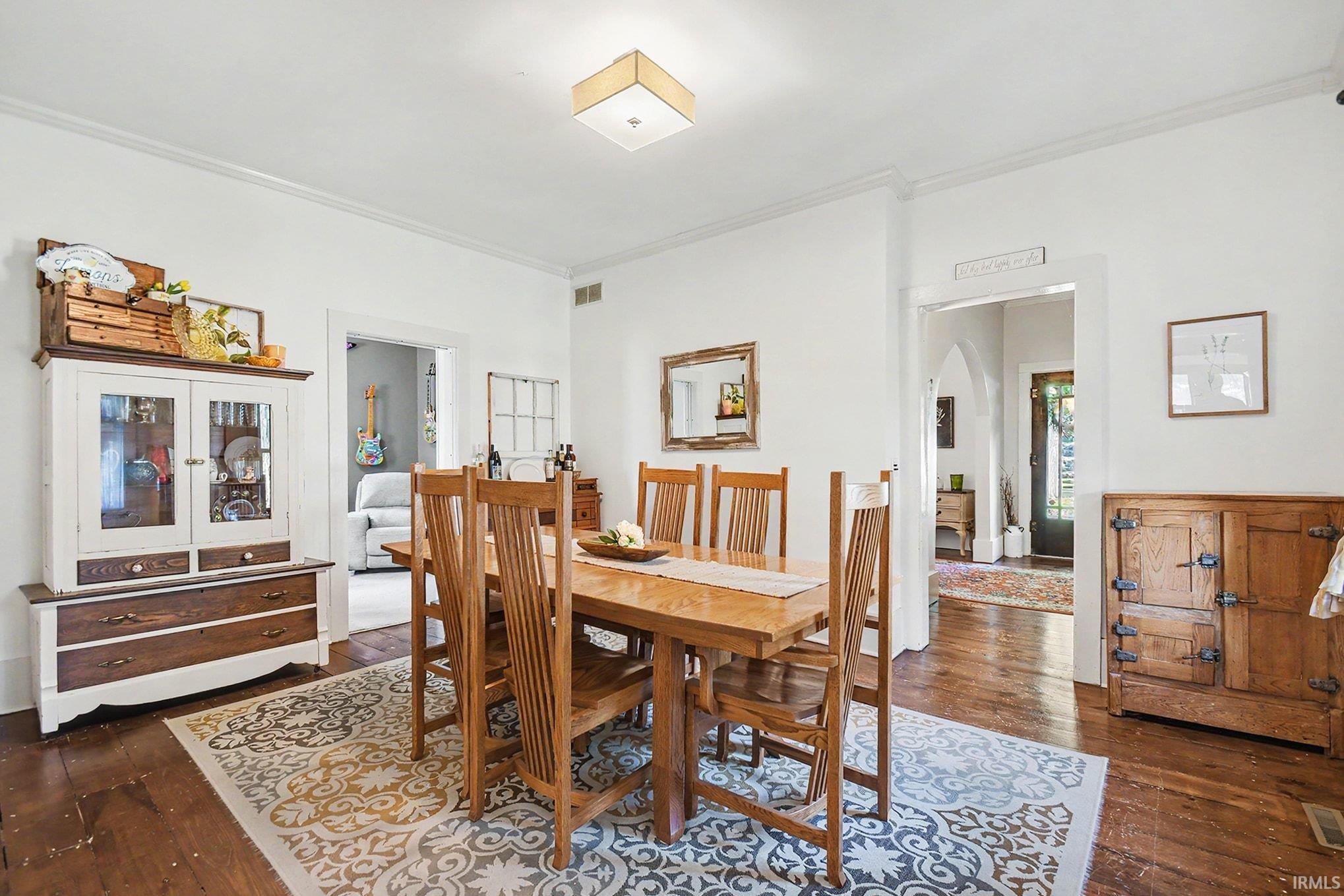Dining area featuring hardwood flooring, white wall finishes, and crown molding