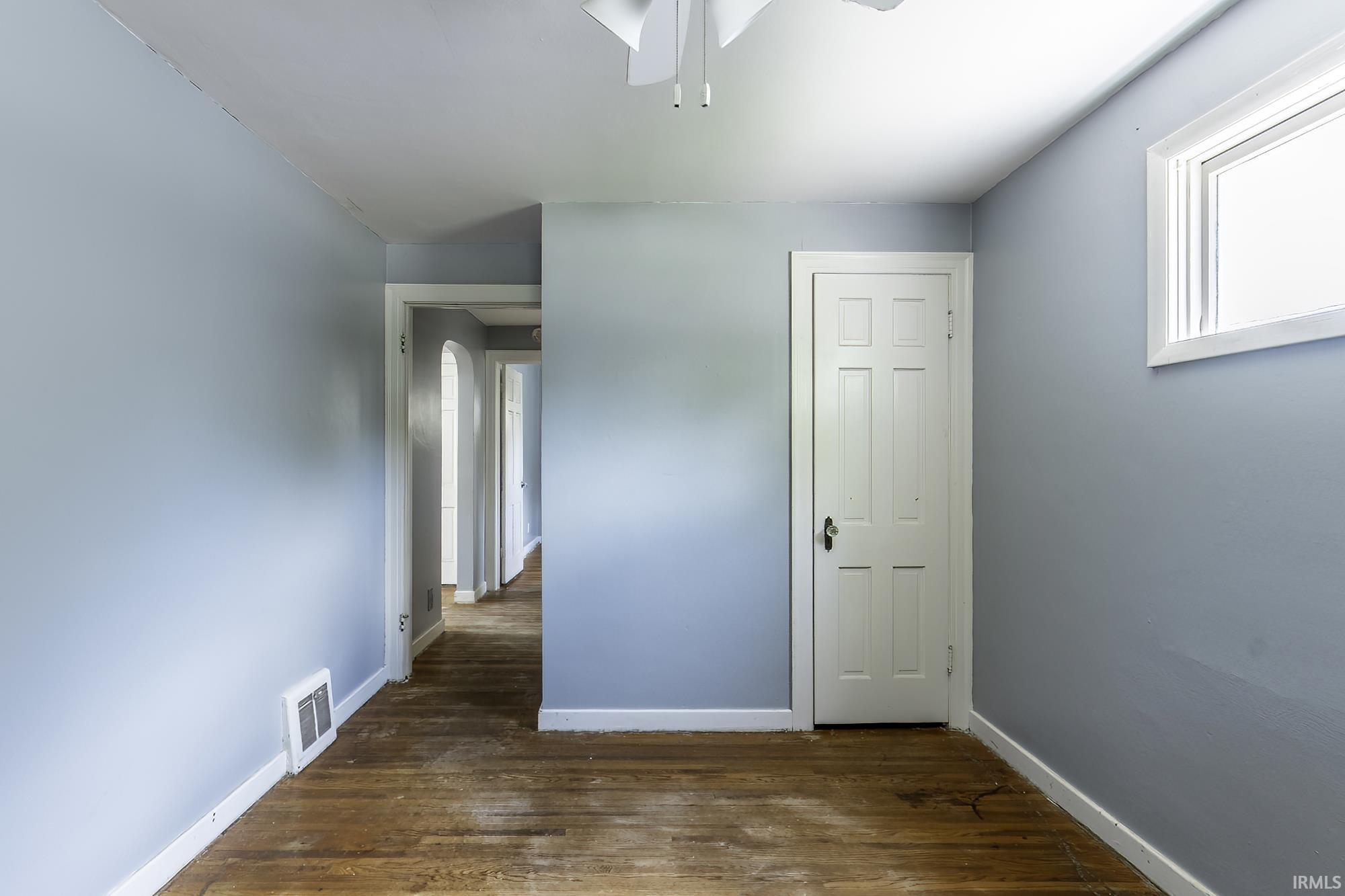 Interior room featuring light blue walls, a white multi-paneled door, and a white-framed window