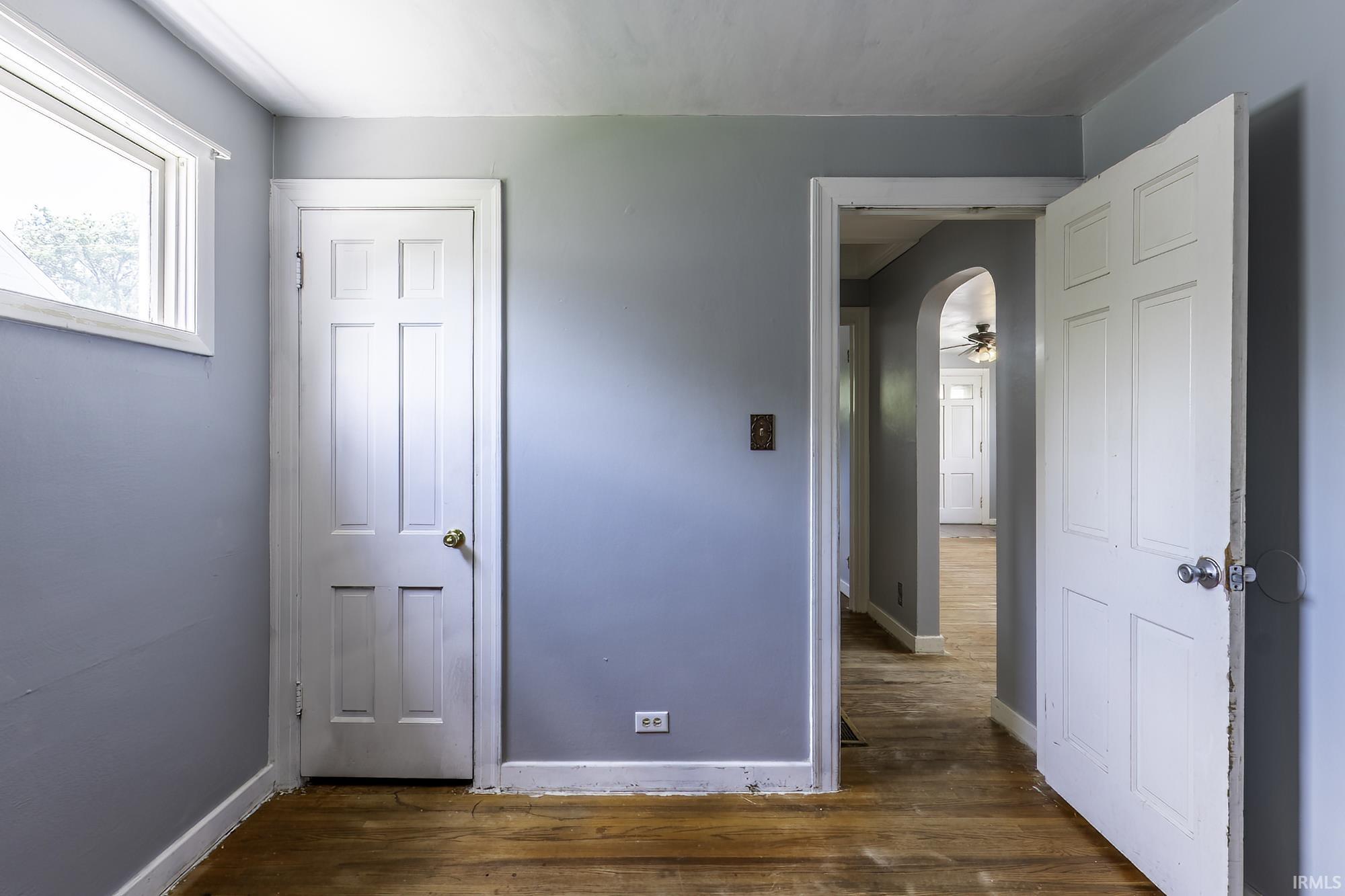 Interior room with wood-finish flooring, light blue-gray walls, and white trim