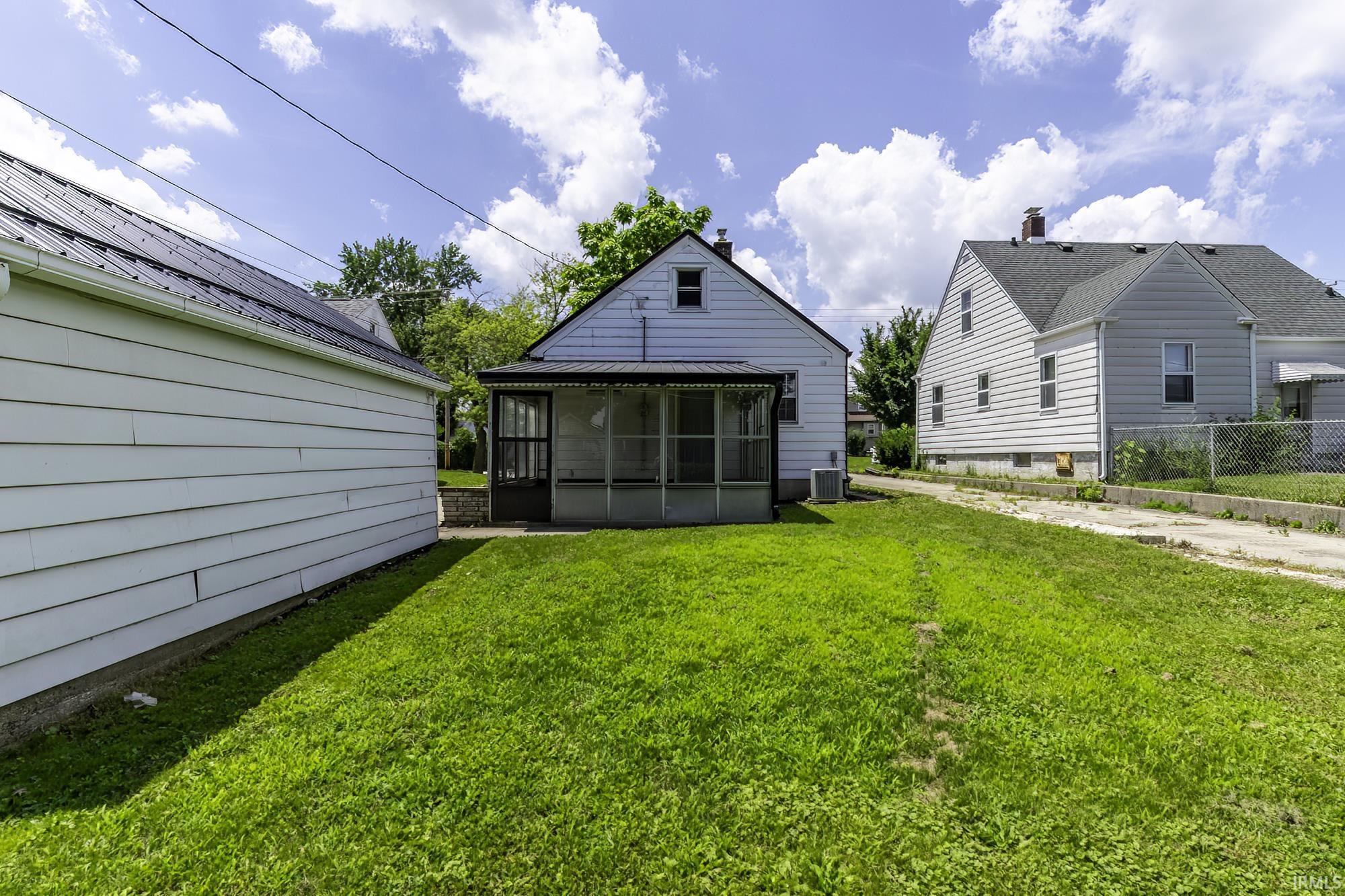 Rear exterior featuring a screened porch, a pitched roof, and white siding