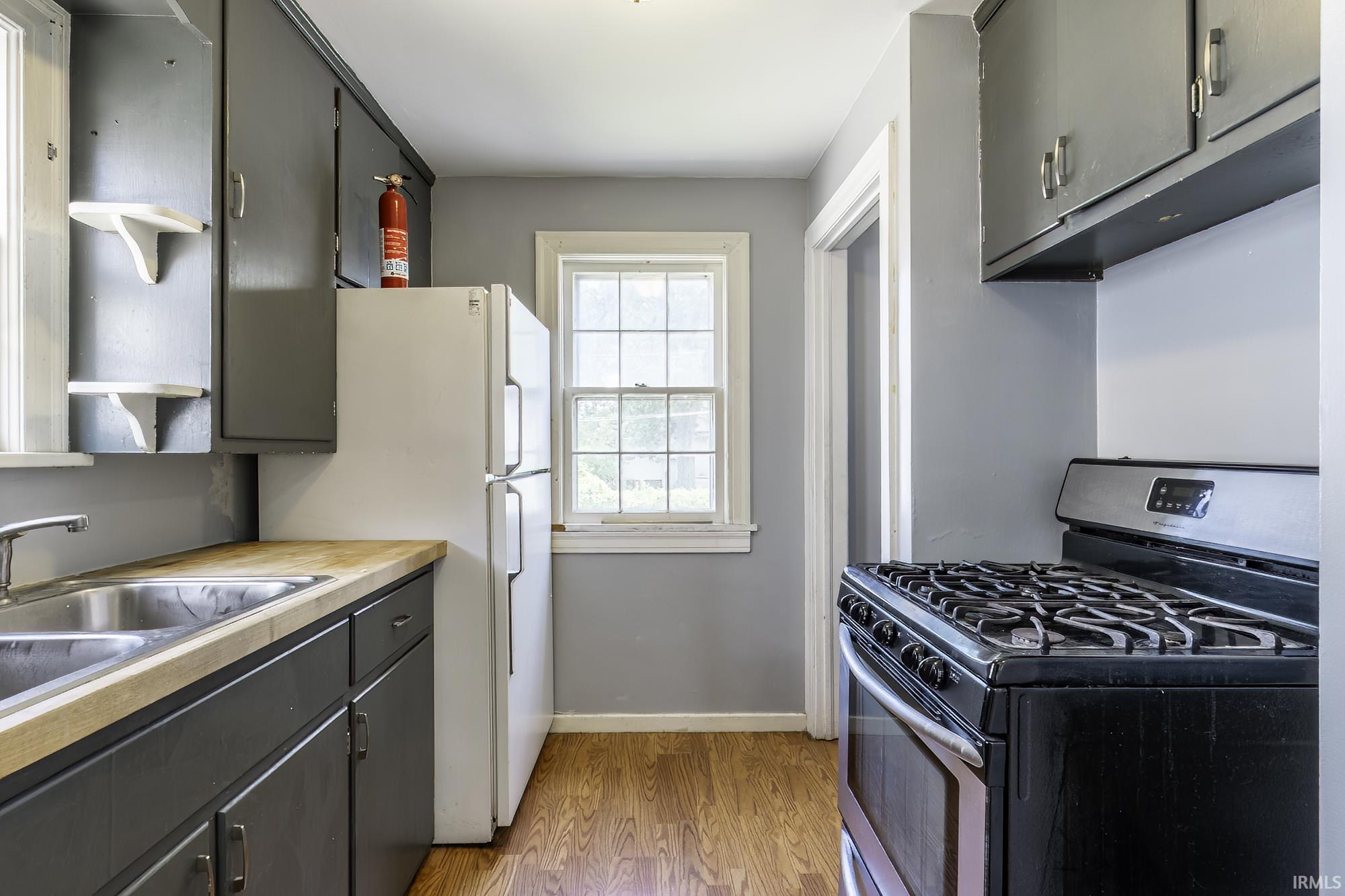 Kitchen with wood-finish flooring, light grey walls, and dark grey cabinetry