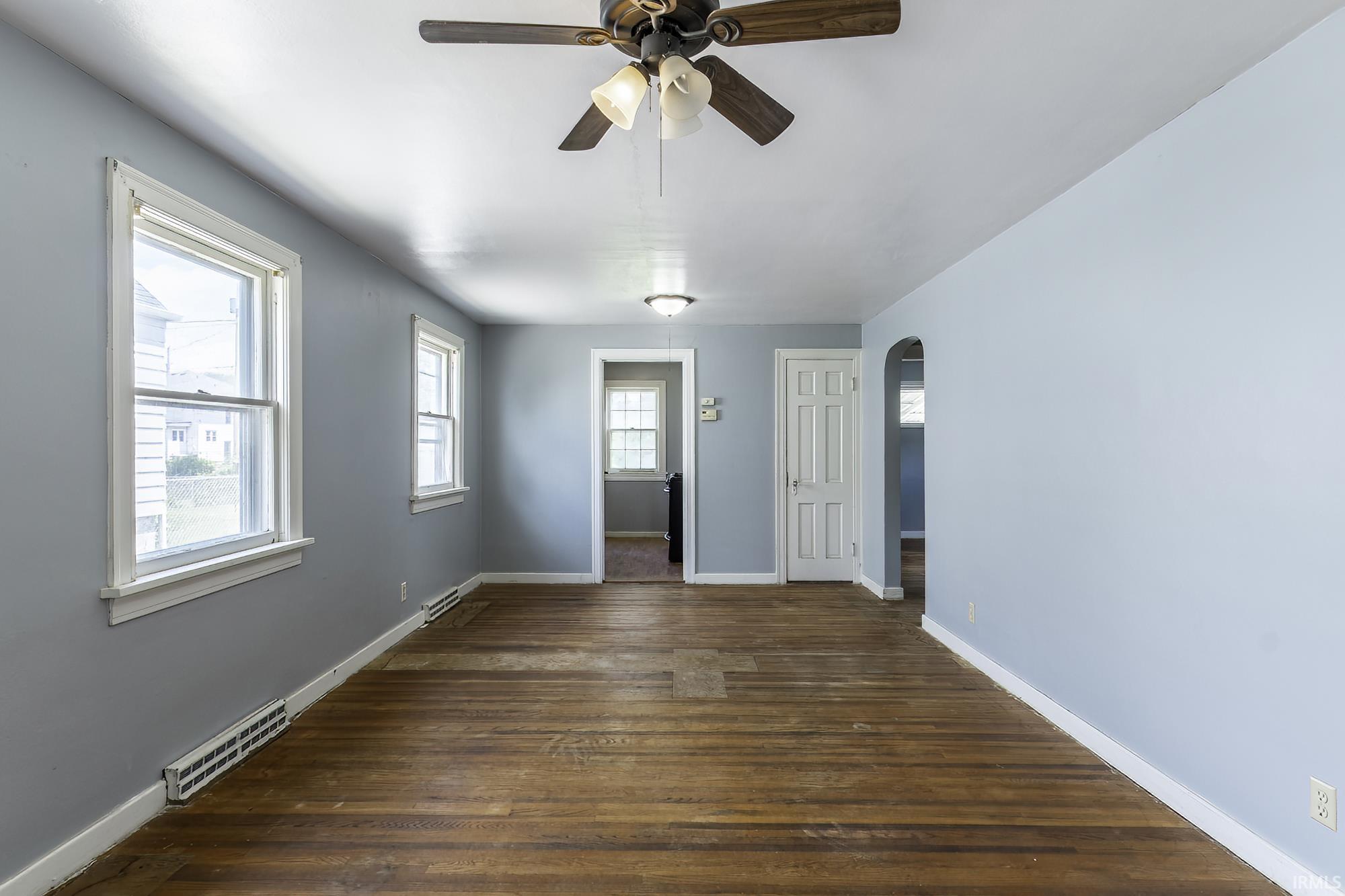 Spacious interior room featuring wood-finish flooring, light blue walls, and white trim
