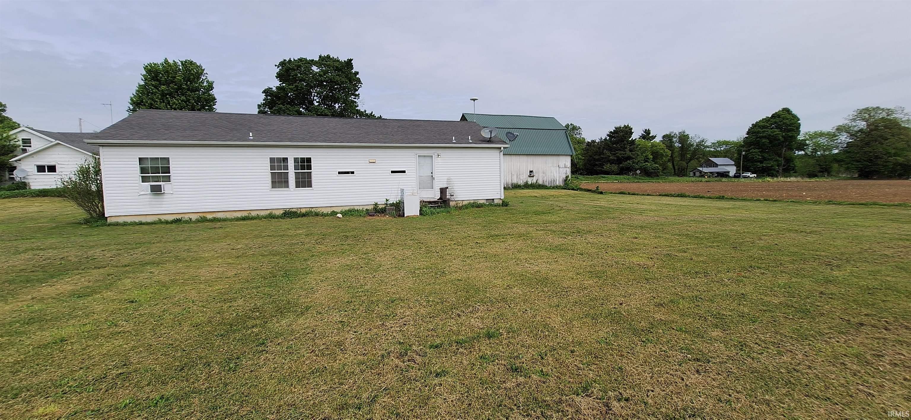 Spacious yard with a white siding structure featuring a gray shingle roof
