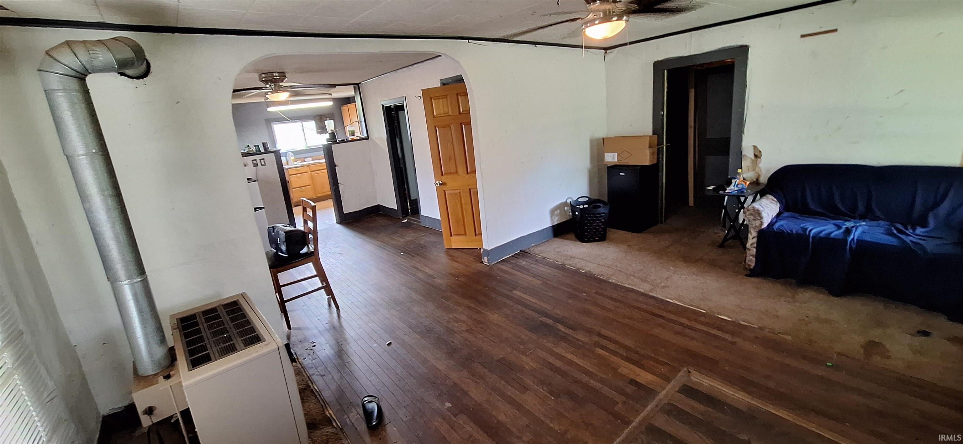 Hardwood flooring throughout the main room, featuring an arched doorway and a built-in furnace unit