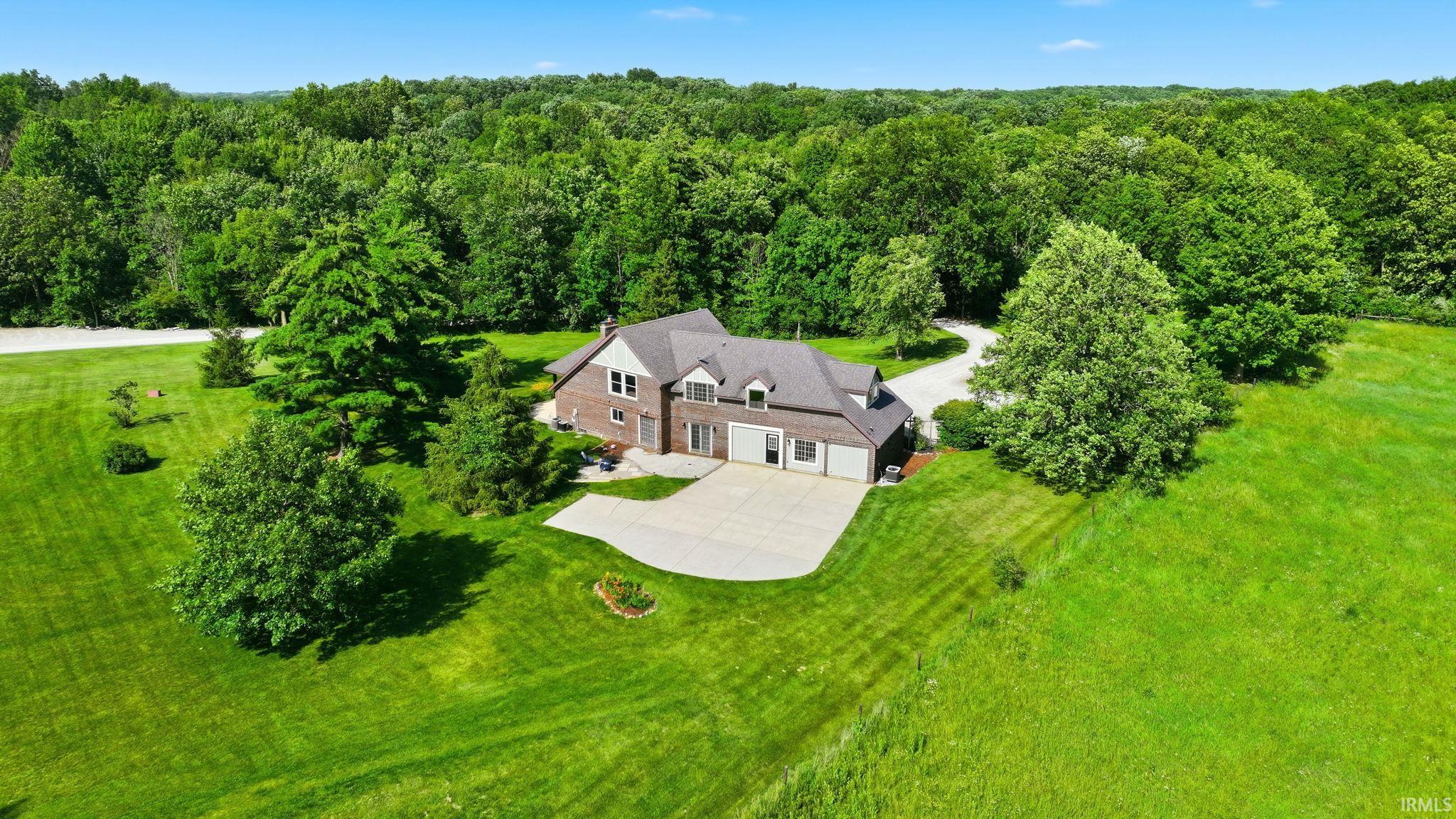 Brick exterior residence with a multi-car garage, set on an expansive lot with mature trees and a manicured lawn