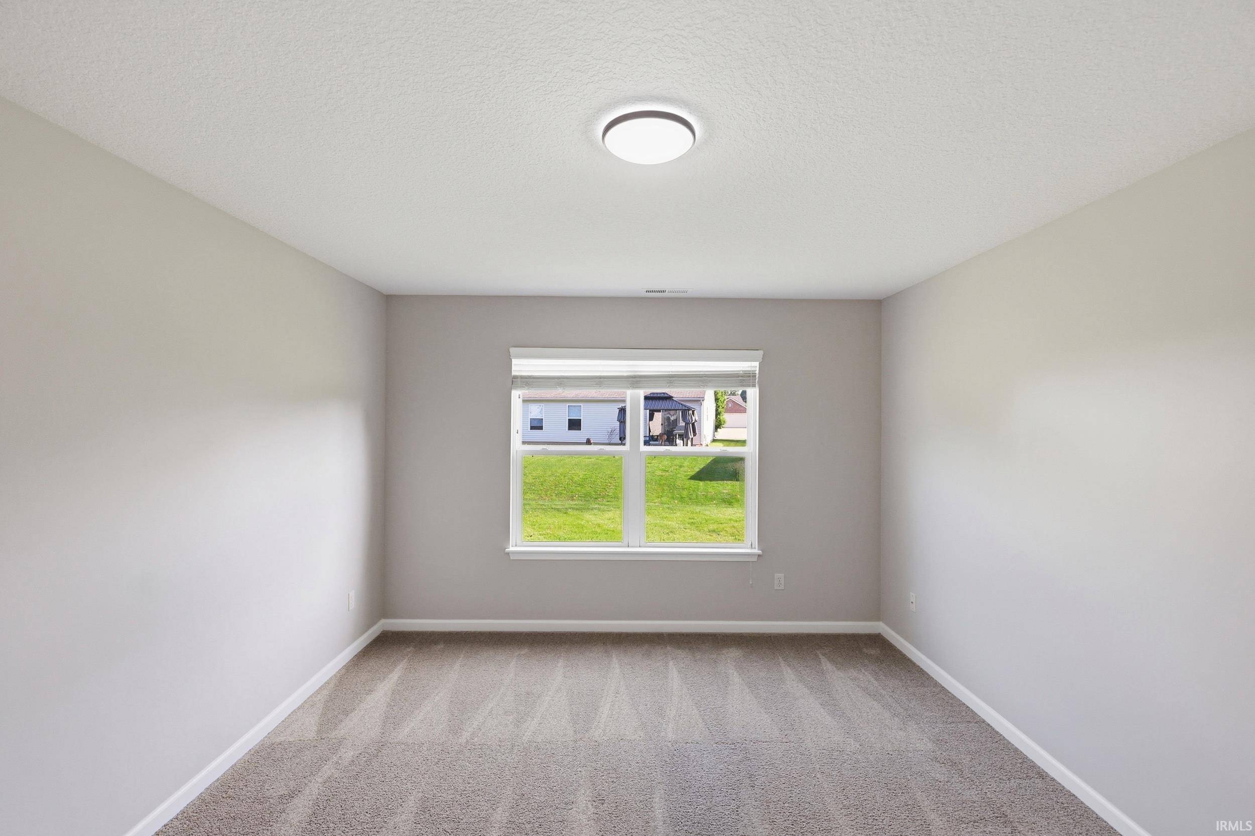Interior room featuring a single window with blinds, light gray wall paint, white trim, and textured gray carpet