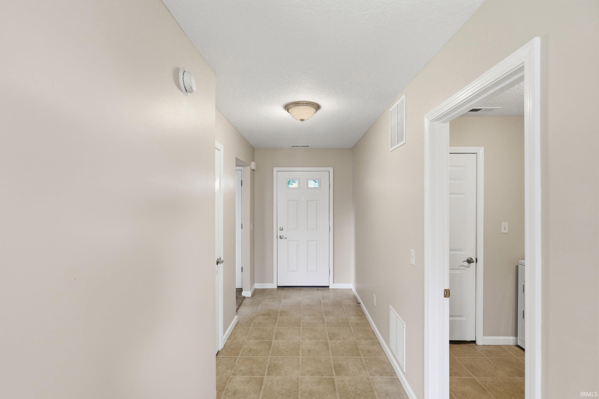 Entryway featuring tile flooring, neutral wall paint, white trim, a recessed ceiling light, and a white paneled door with decorative glass inserts