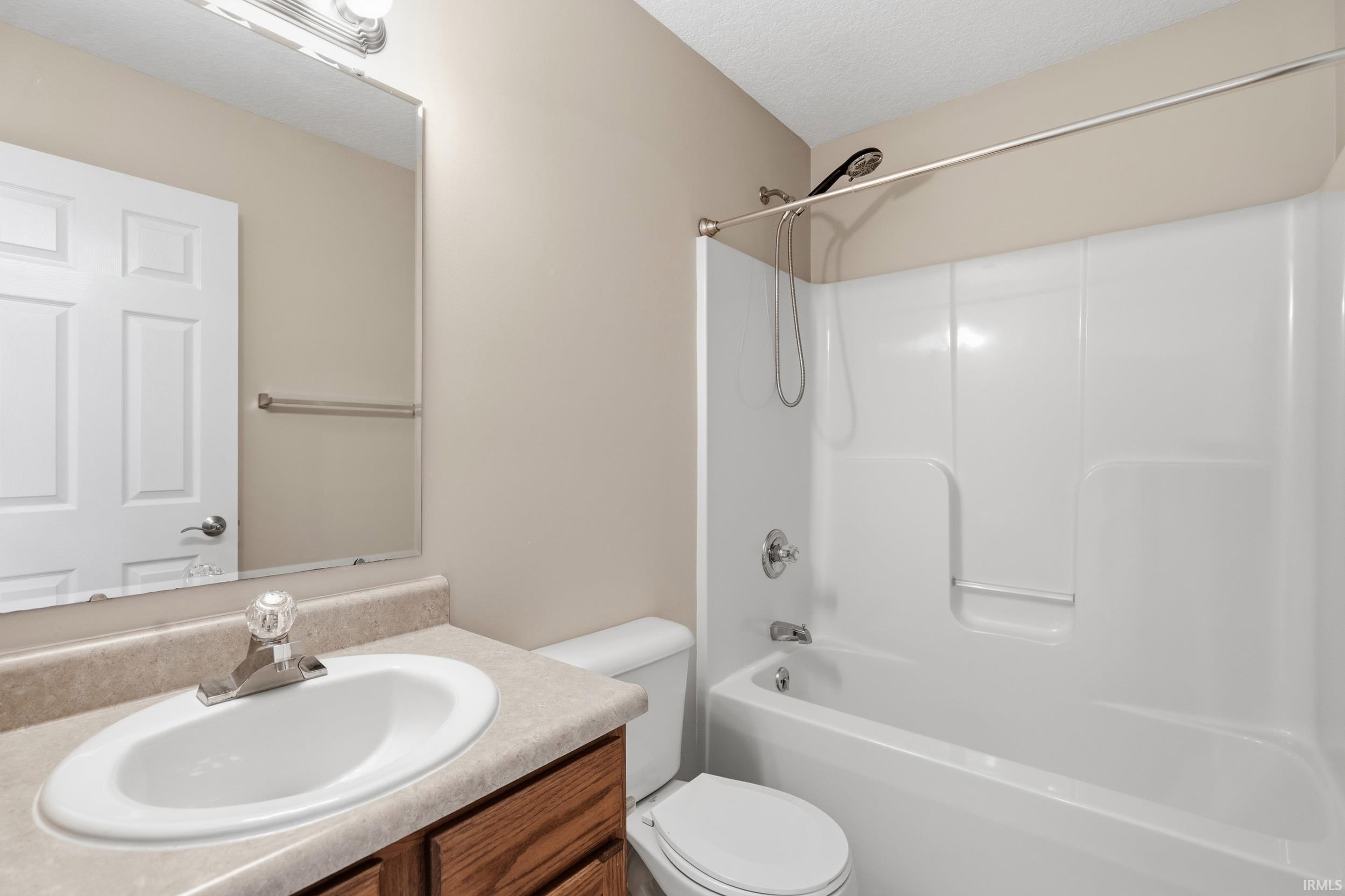 Full bathroom featuring a single vanity with wood-finish cabinetry and a molded countertop