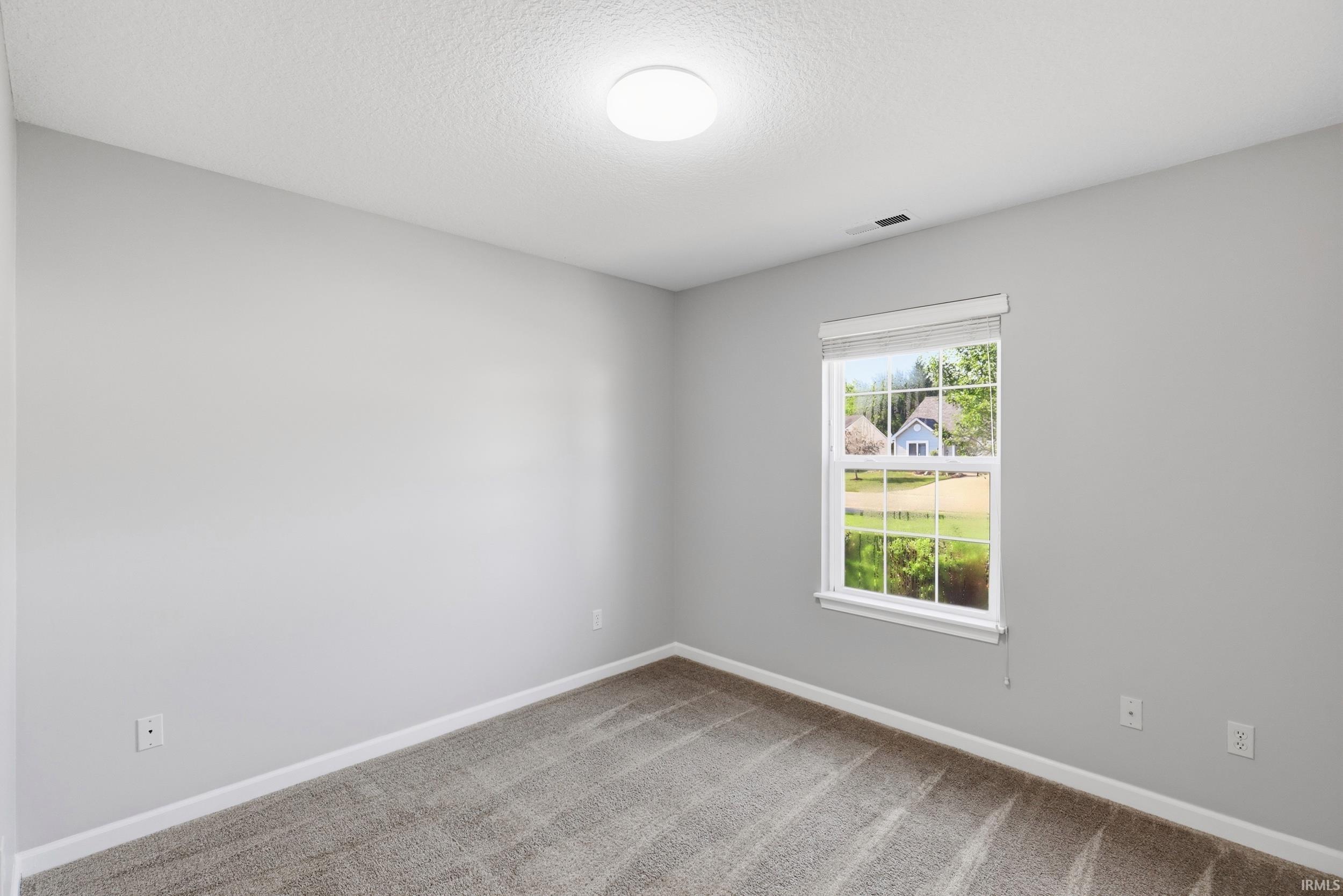 Interior room featuring light gray wall paint, white trim, and textured carpet flooring