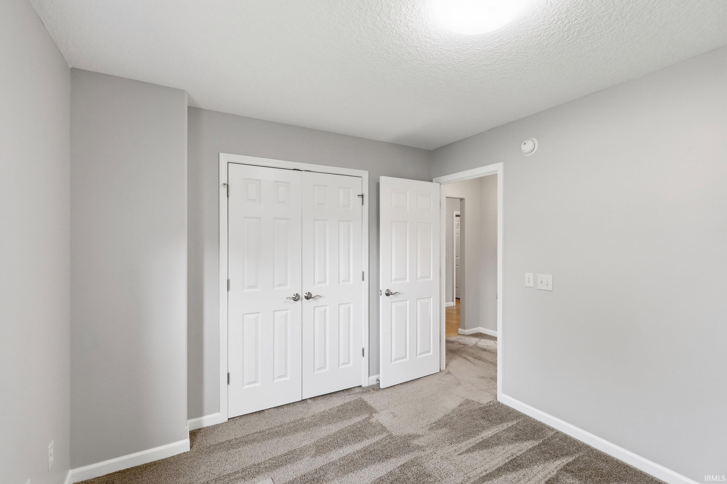 Light gray wall paint with white trim, featuring a bi-fold closet door and a paneled entry door