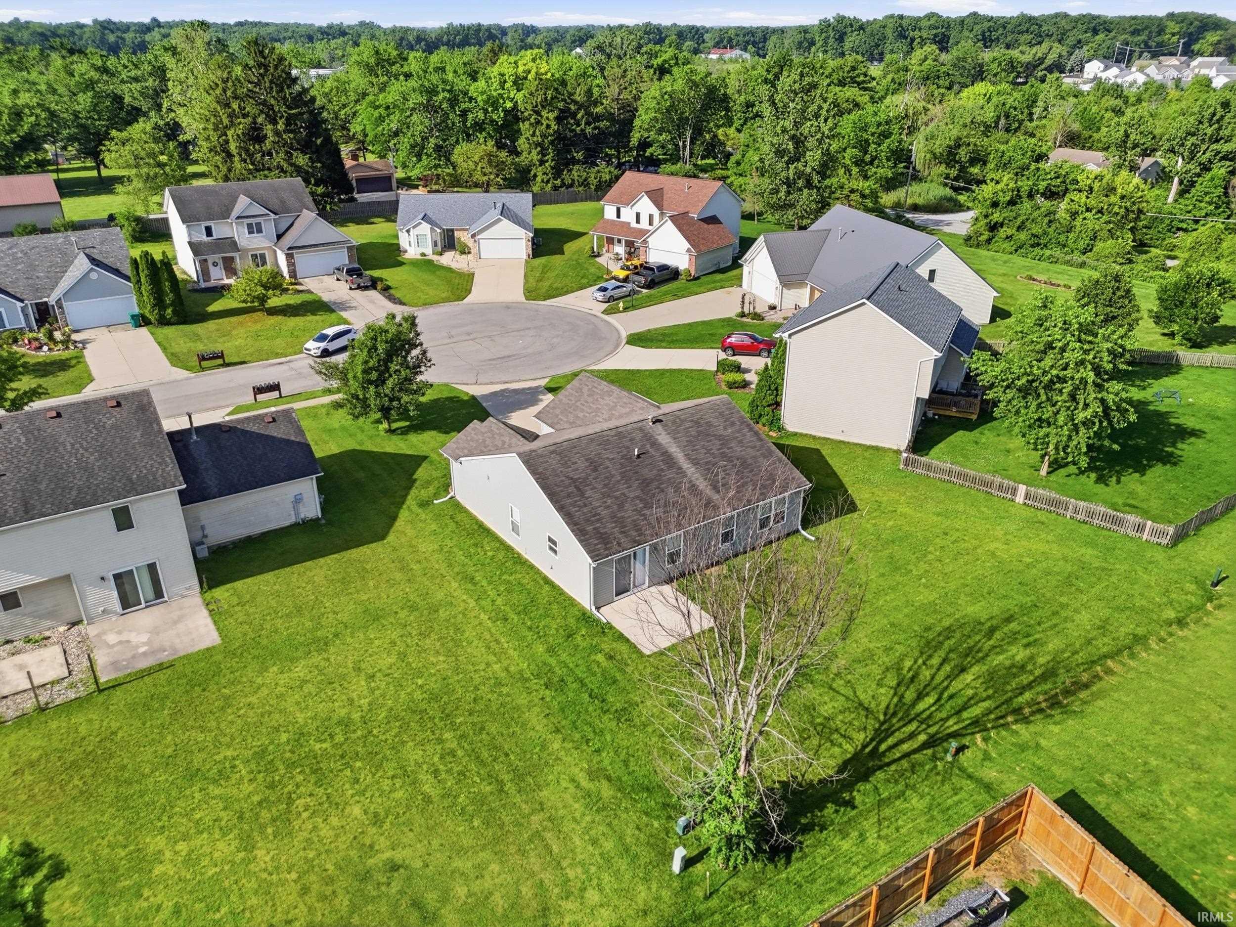 Spacious property featuring a large green lawn, a concrete patio, and a mature tree