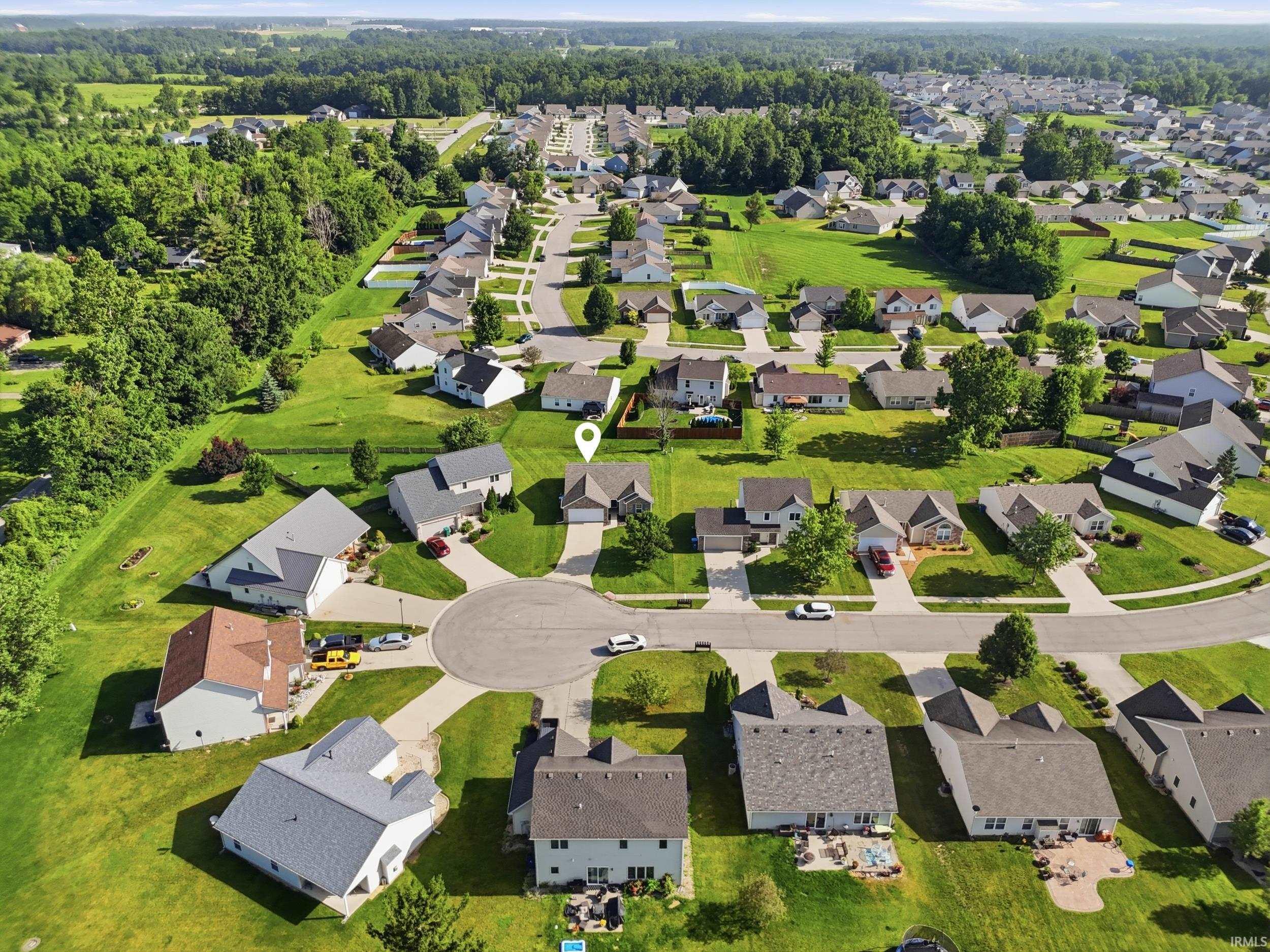 Aerial view of a suburban neighborhood featuring residential properties with green lawns and paved streets