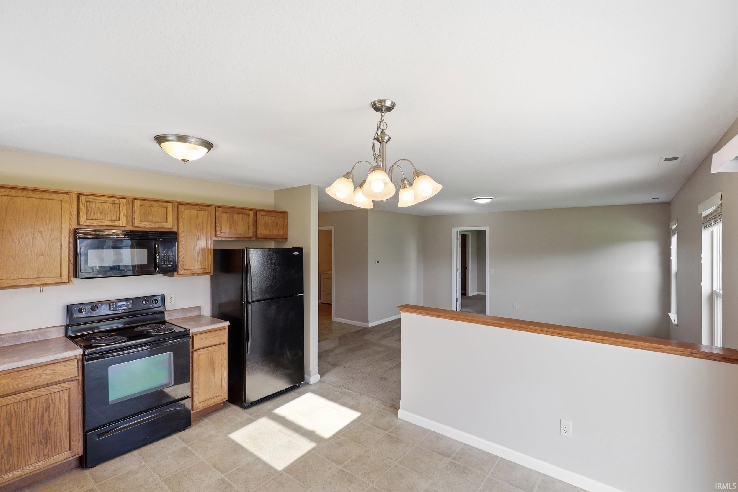 Kitchen featuring wood-finish cabinetry, black appliances, and tile flooring