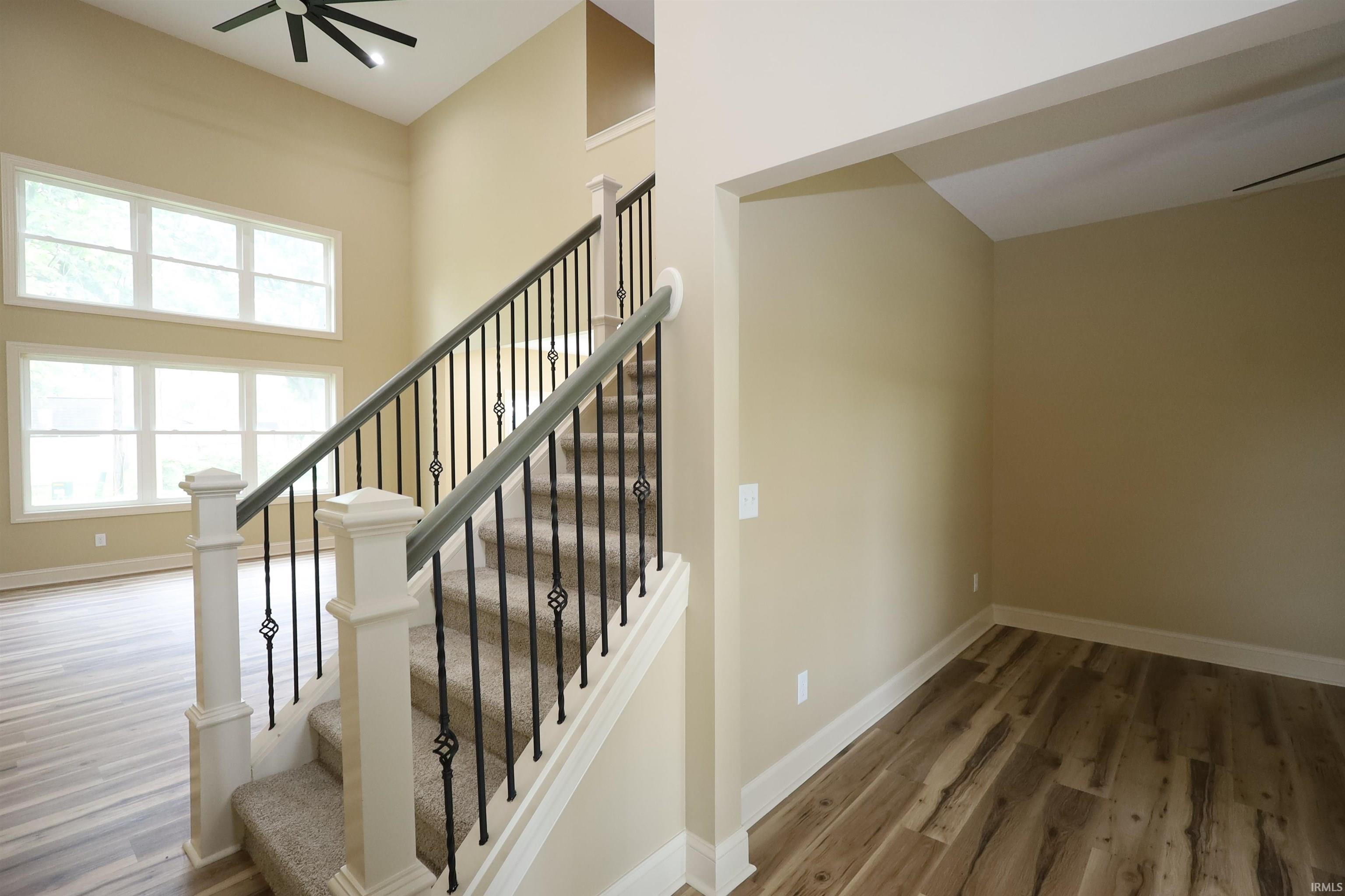 Staircase featuring wrought iron balusters and carpeted treads