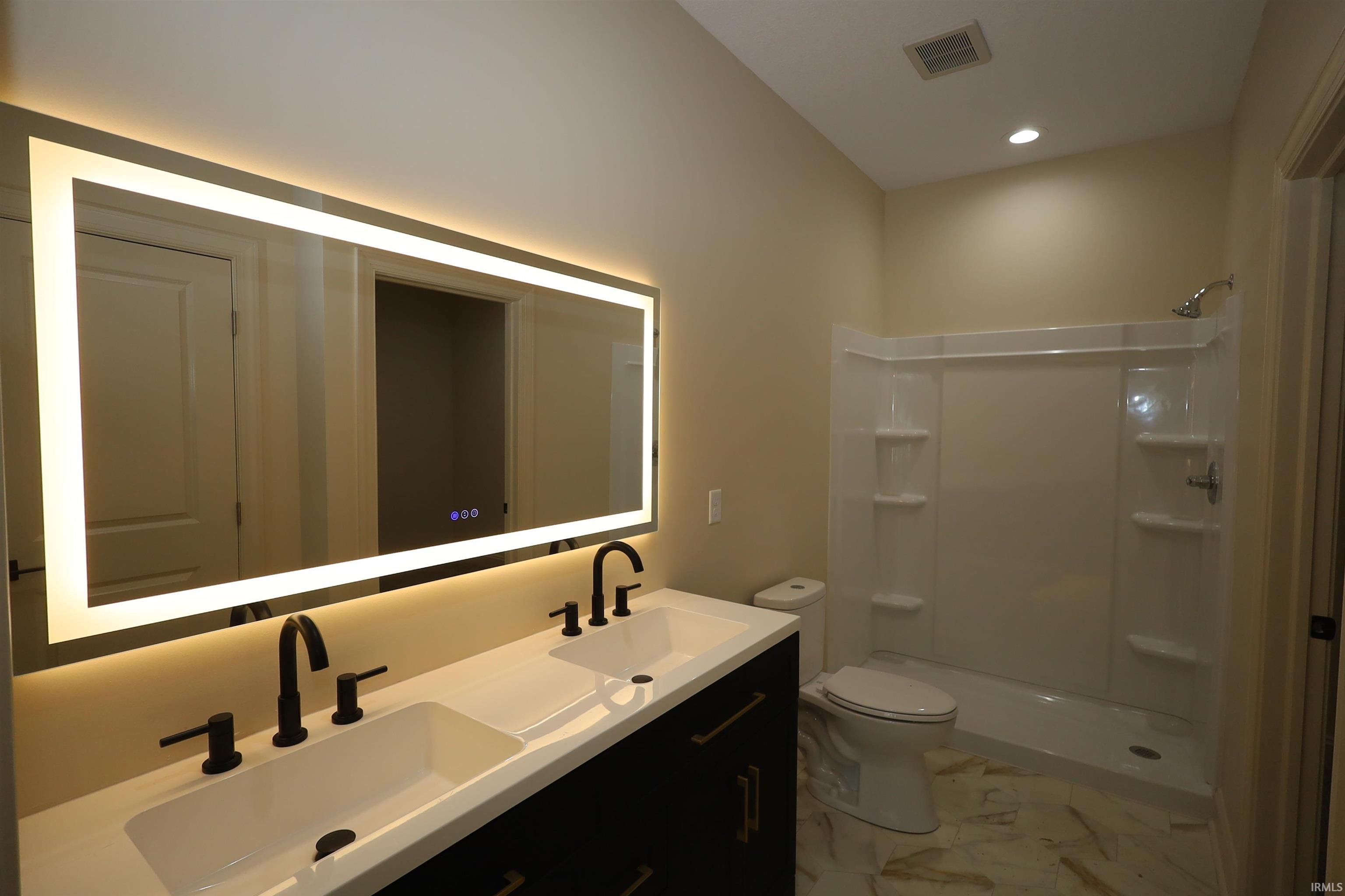 Double vanity with matte black fixtures, an illuminated rectangular mirror, and a white countertop