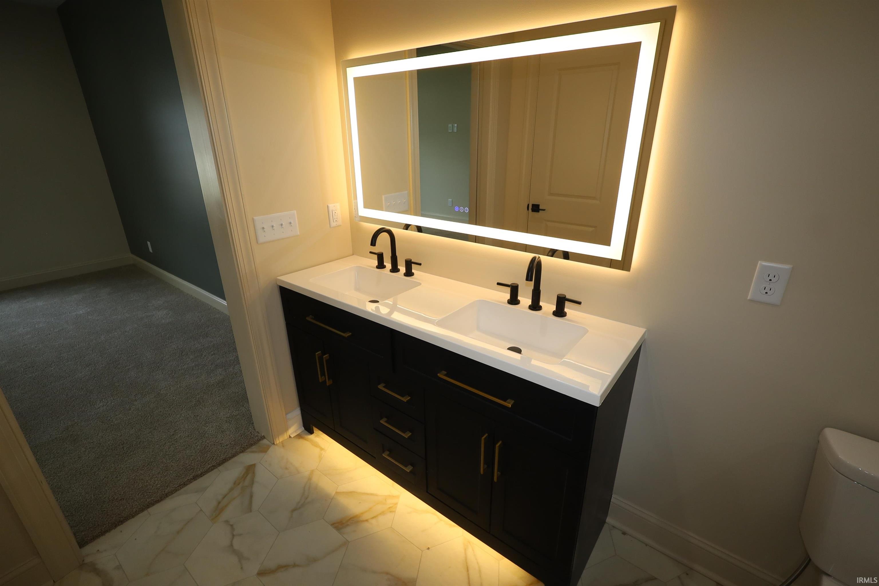 Dual vanity with integrated sinks, a white countertop, and dark cabinetry with gold-tone hardware