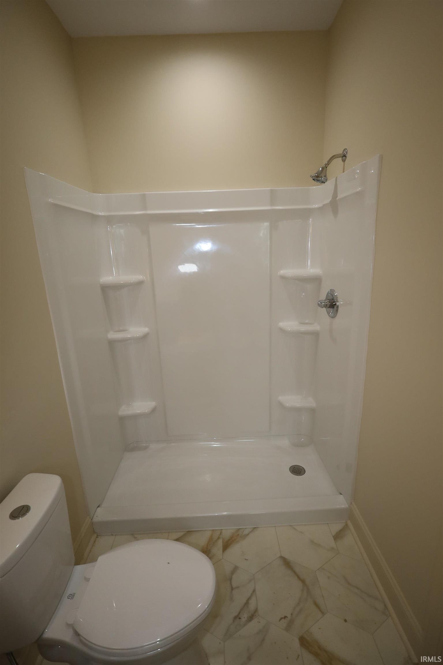 White composite shower stall with integrated shelving and chrome fixtures