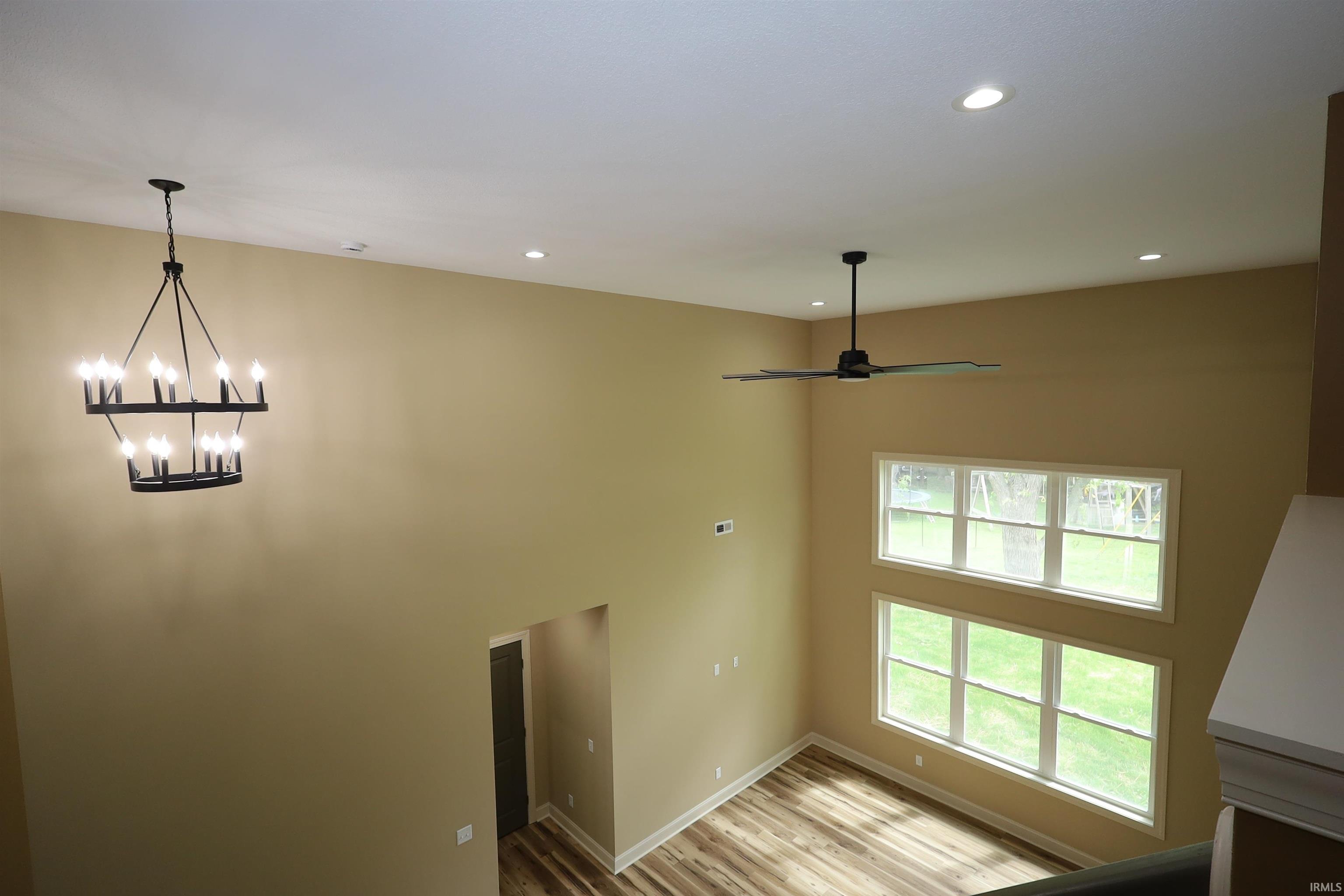 Two-story room featuring a multi-tiered chandelier, ceiling fan, and recessed lighting