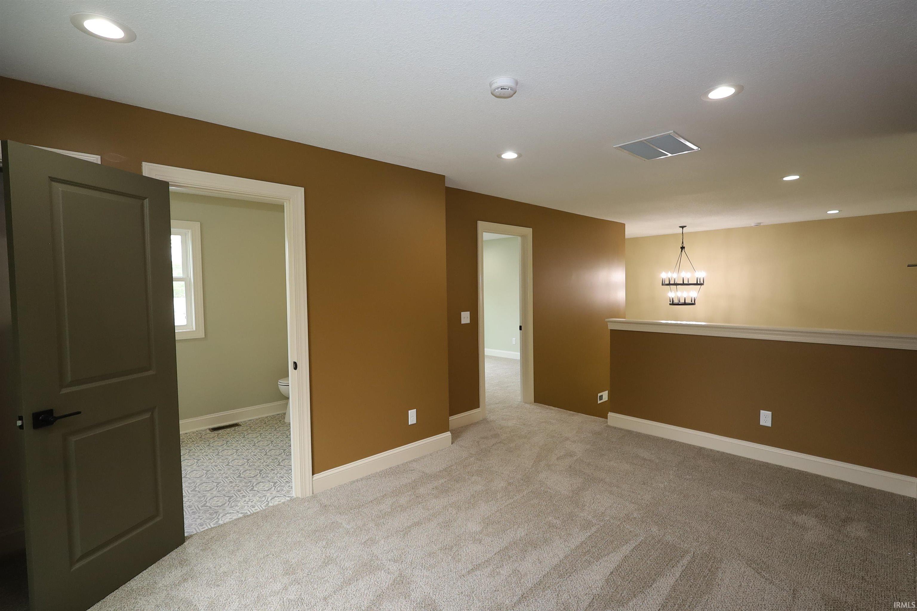 Carpeted interior space featuring recessed lighting and a contemporary chandelier