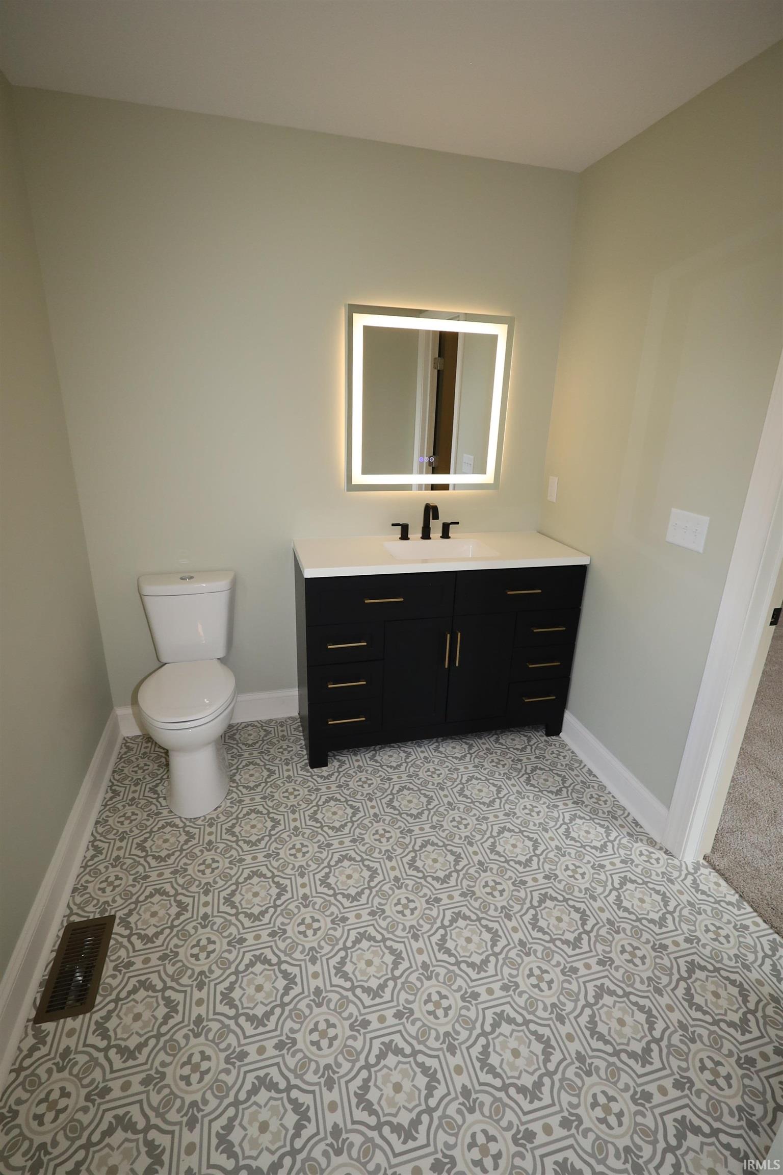 Bathroom featuring a black vanity with gold-tone hardware, white countertop, and a vessel sink with a matte black faucet