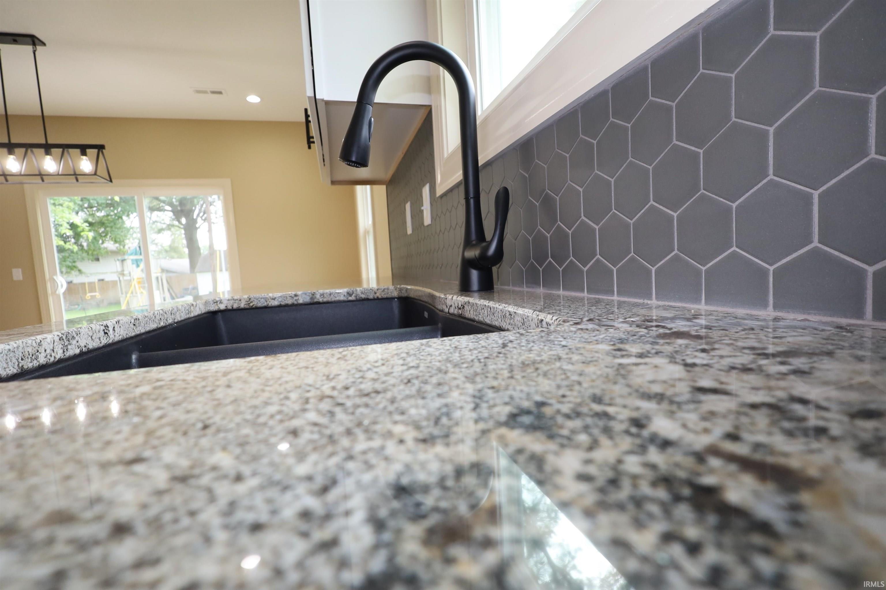 Granite countertops featuring an undermount black double sink and a matte black gooseneck faucet