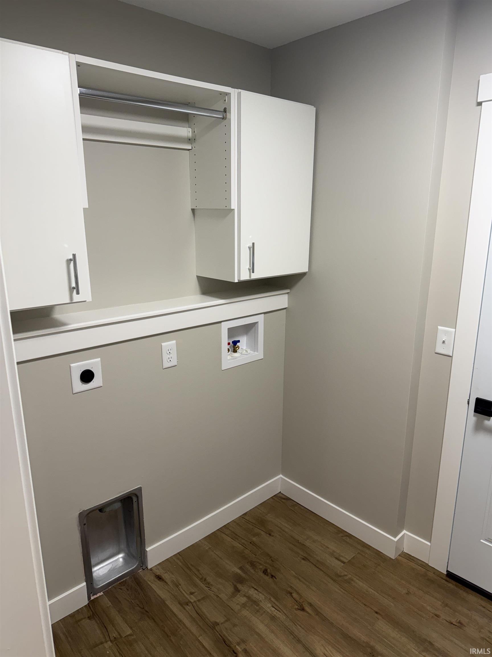 Dedicated utility space featuring neutral wall tones, wood-finish flooring, and crisp white baseboards