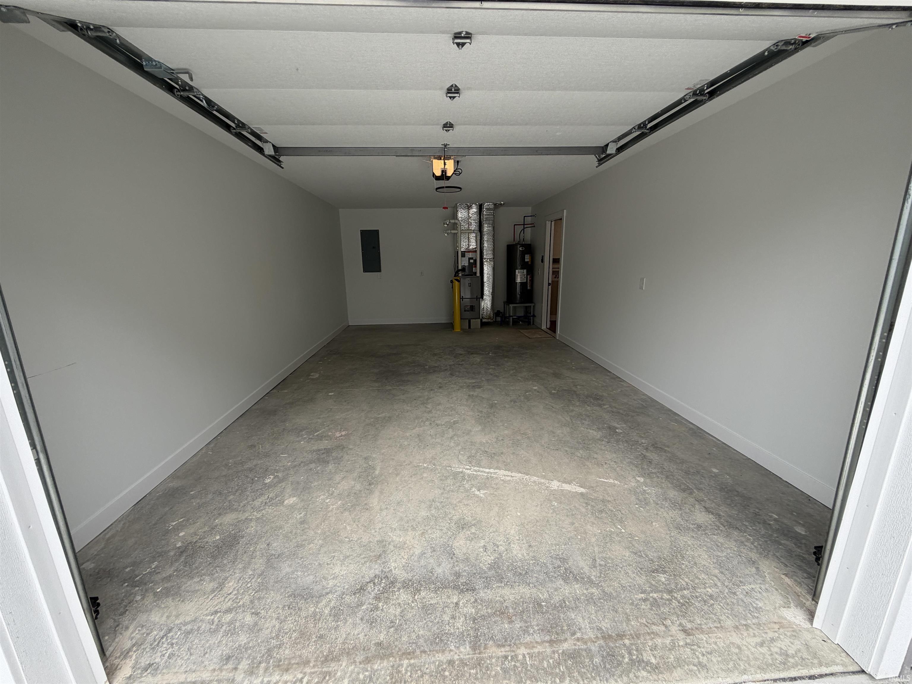 Spacious garage featuring a concrete floor, light gray walls, and exposed ceiling tracks