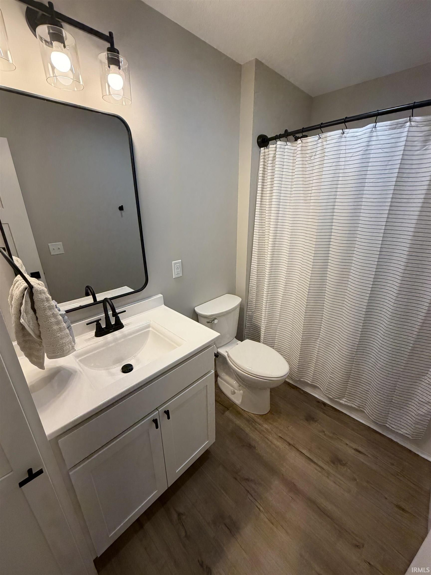 Bathroom featuring a white vanity with integrated sink, matte black faucet, and coordinating mirror