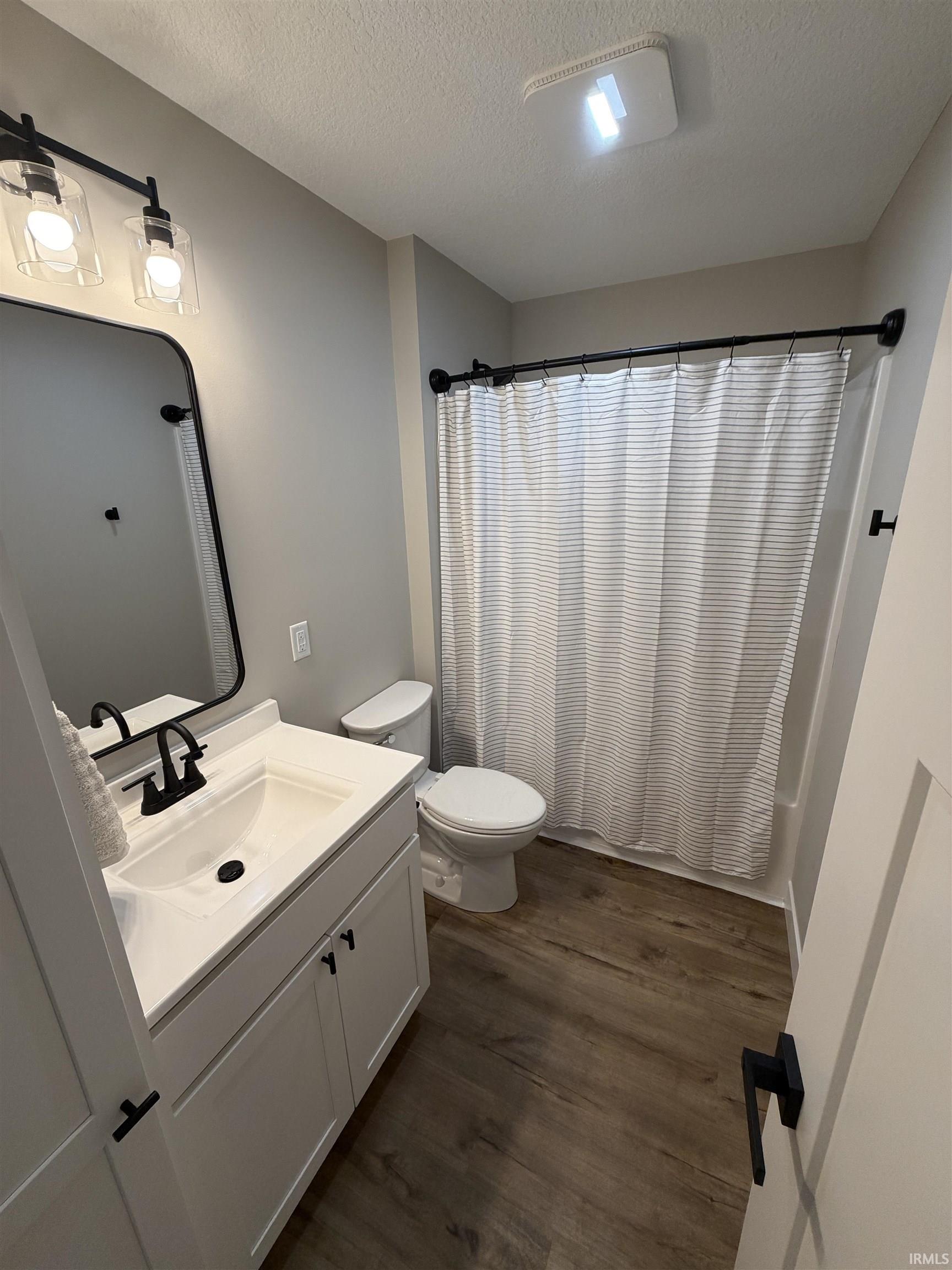 Full bathroom featuring a white vanity with integrated sink, black matte faucet, and matching light fixture