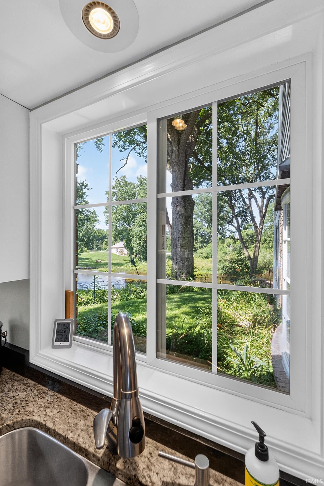 Kitchen window with white trim, a stainless steel faucet, and a granite-style countertop