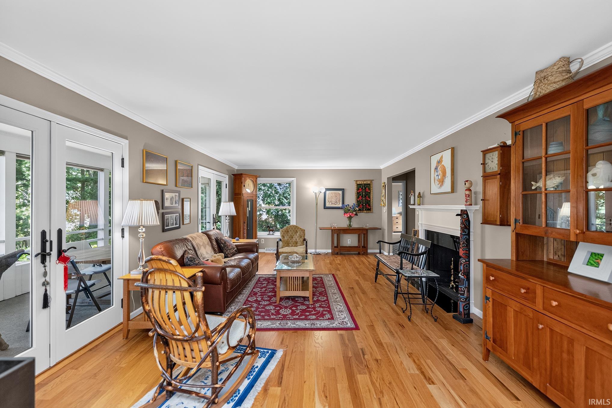 Living area featuring wood-finish flooring, a fireplace with a white mantel, and light gray wall paint